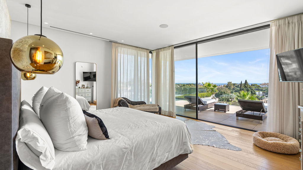 Elegant bedroom with sea view and sliding glass doors.