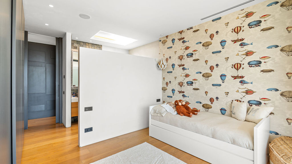 Child's bedroom with whimsical balloon wallpaper and a bed.