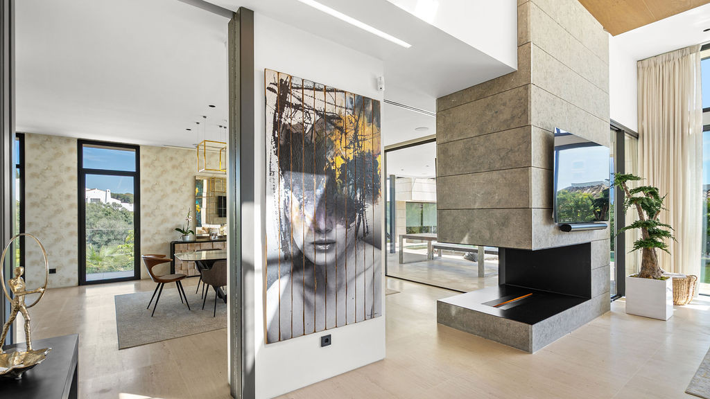 Living area with open layout, modern fireplace, and artwork on the wall, large windows for natural light.