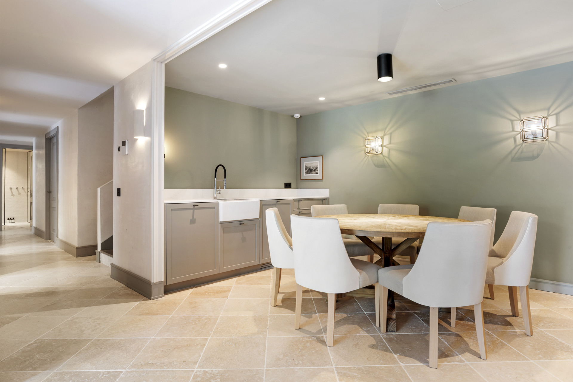 Bright dining area with a round wooden table and six upholstered chairs.