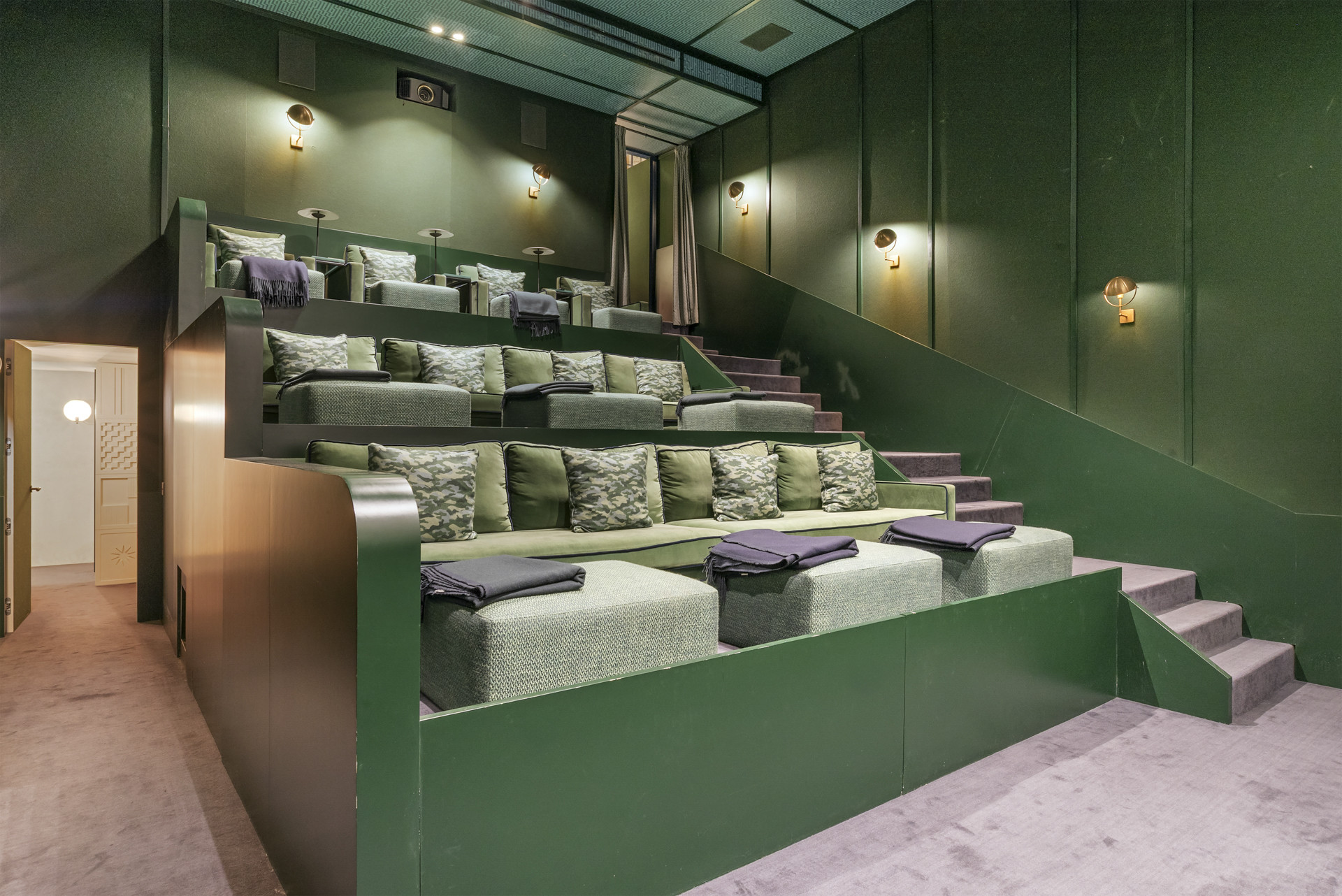 Home theater with tiered seating in rich green tones.