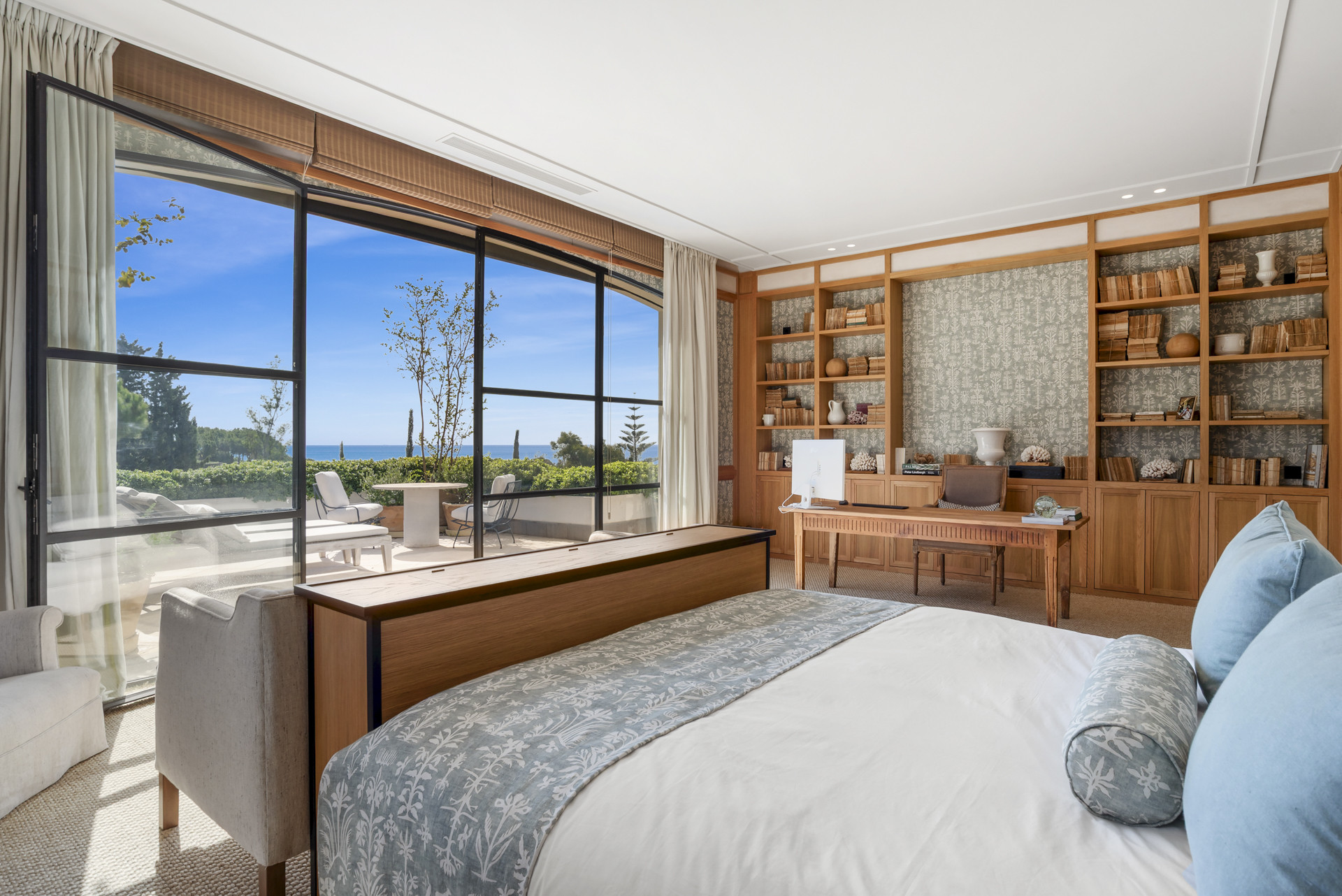 Bedroom showcasing a desk, bookshelves and windows with views outside.