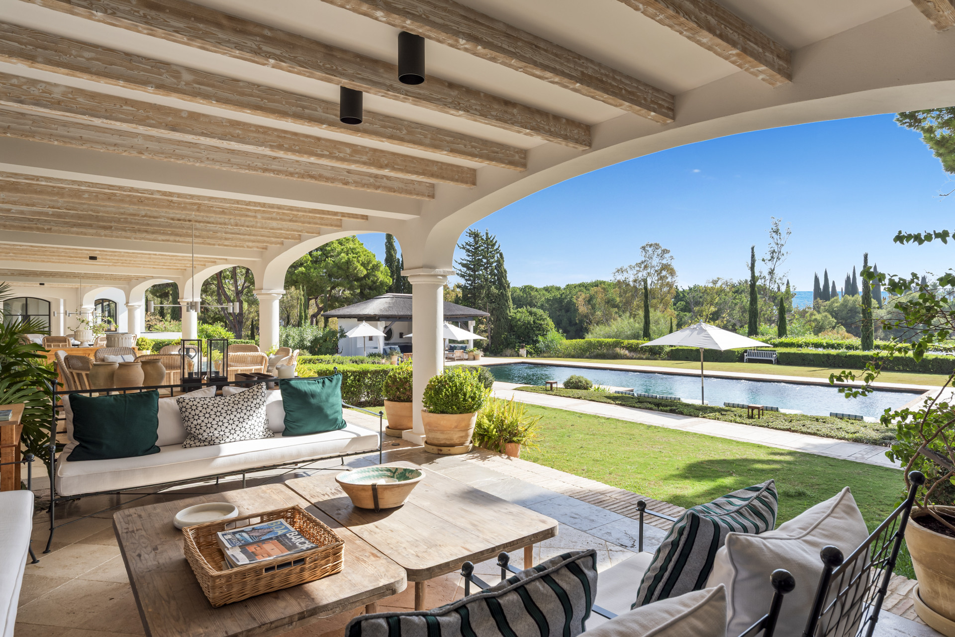 Covered patio with seating and a view of the pool and garden area.