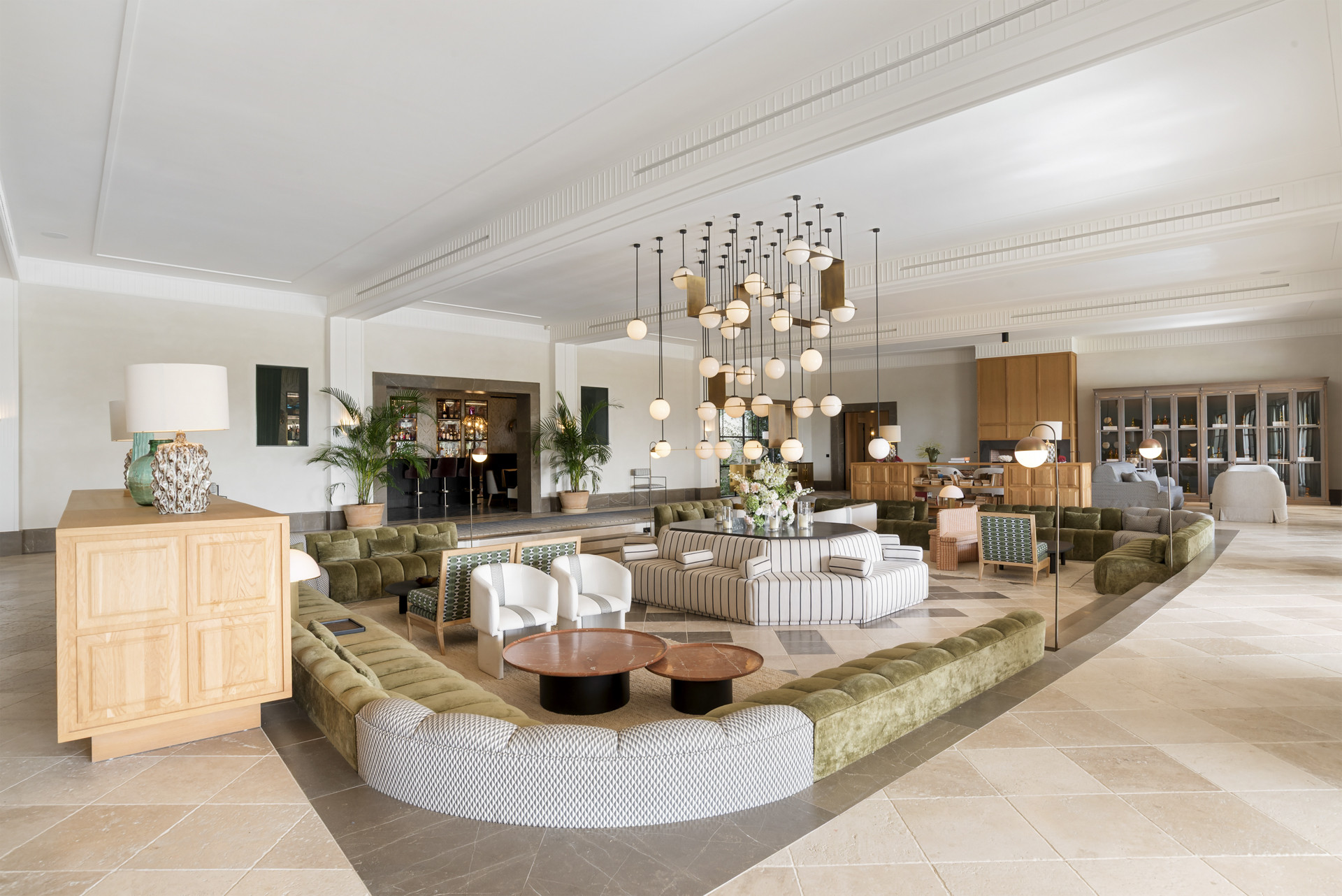 Open living area with ample seating, pendant lights, and a central bar area, all in natural tones.
