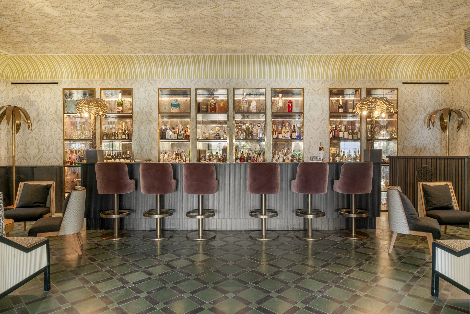 Stylish bar area with a well-stocked liquor display and plush seating in a sophisticated setting.