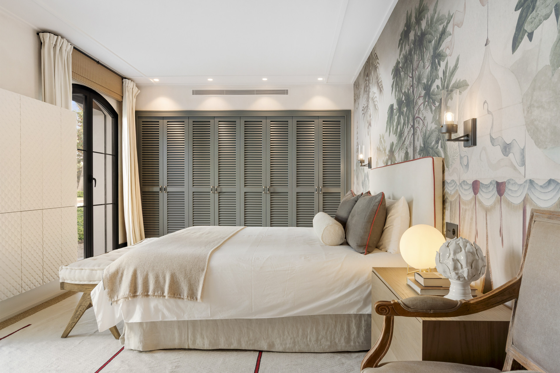 Bedroom with a textured mural, a plush bed, and cabinetry along the wall.