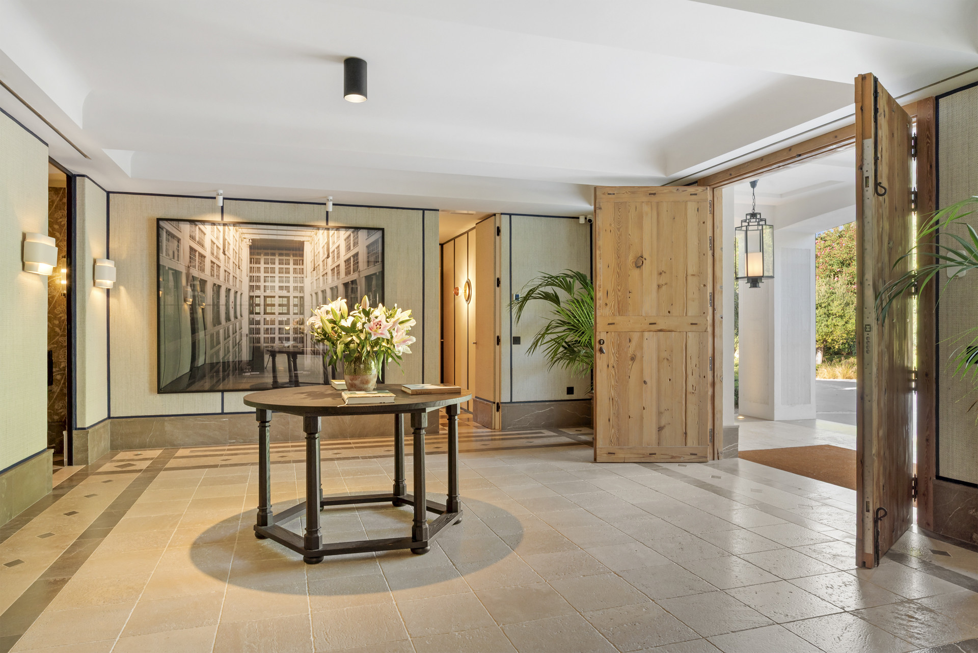Entryway featuring a round table with flowers and wooden double doors.