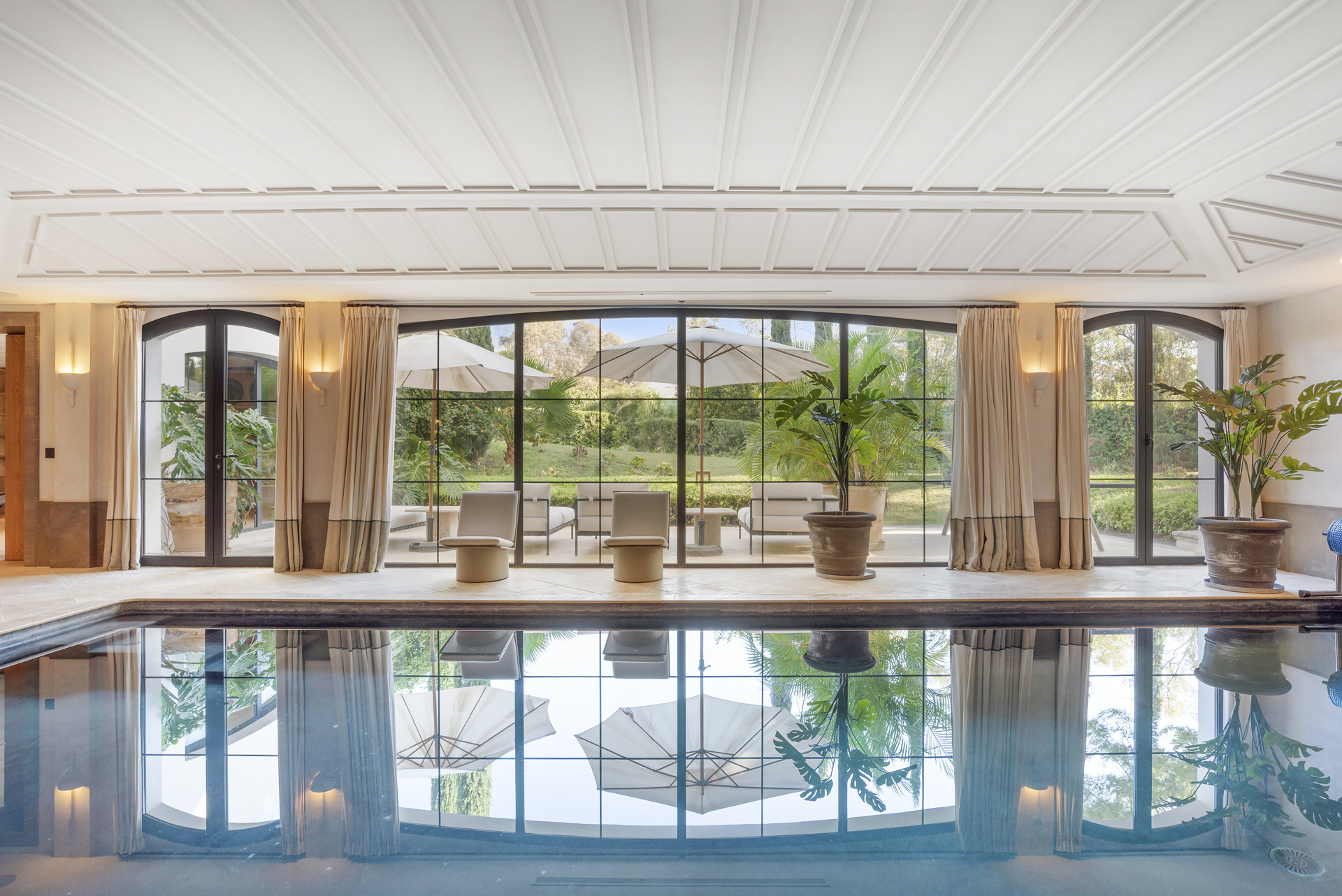 Indoor pool area featuring large windows overlooking the garden.