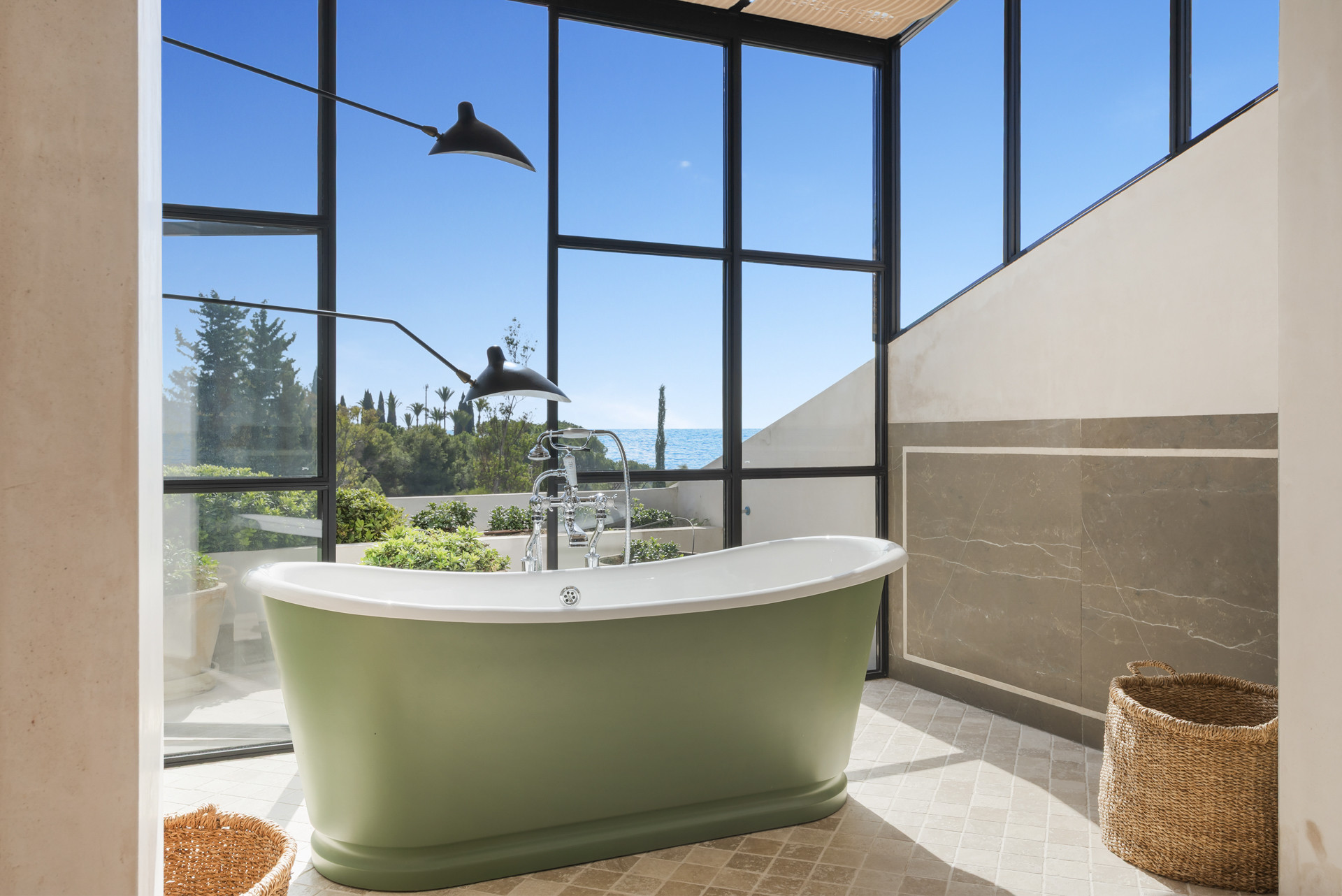 Modern bathroom highlighting a green bathtub and large windows framing ocean scenery.