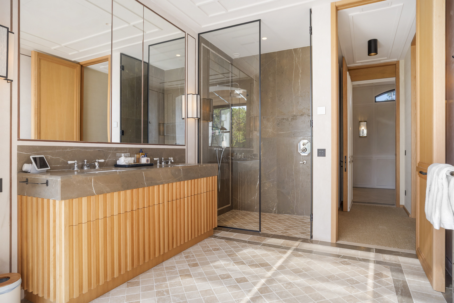 Stylish bathroom featuring a glass shower, double sink, and light wood details.