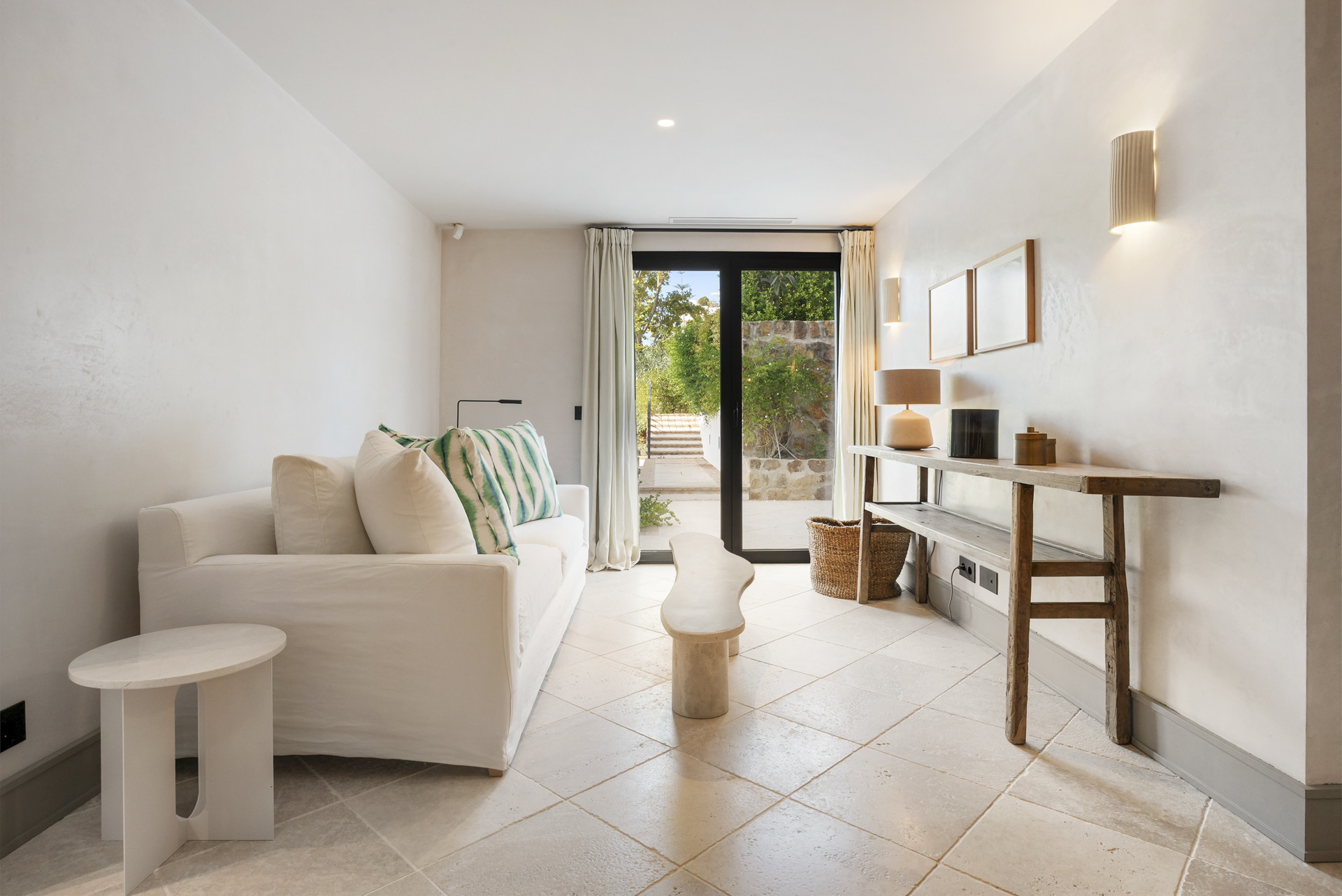 Cozy lounge with a white sofa, small table, and garden view.