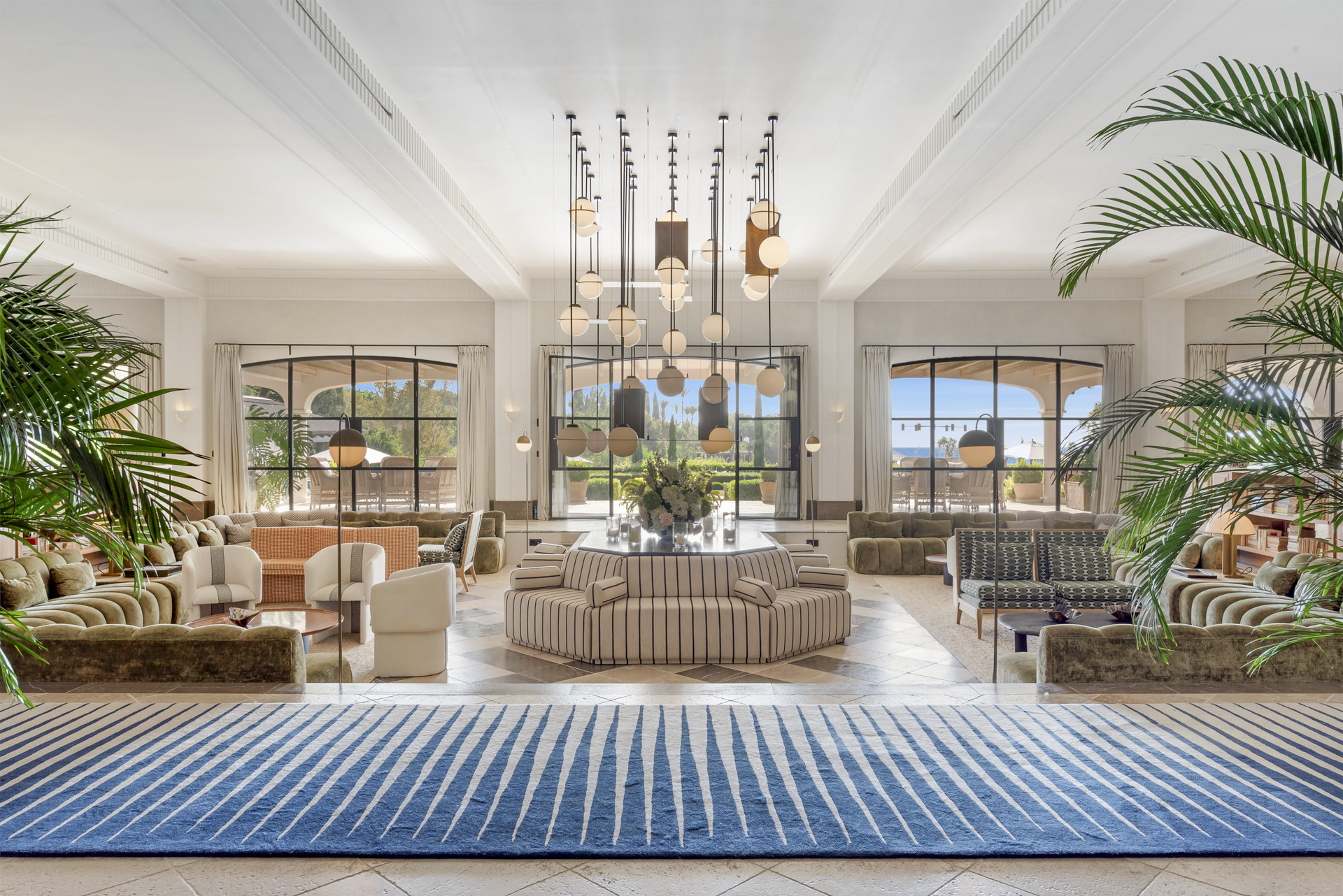 Bright living room featuring large windows, diverse seating, and a greenery view through the glass.