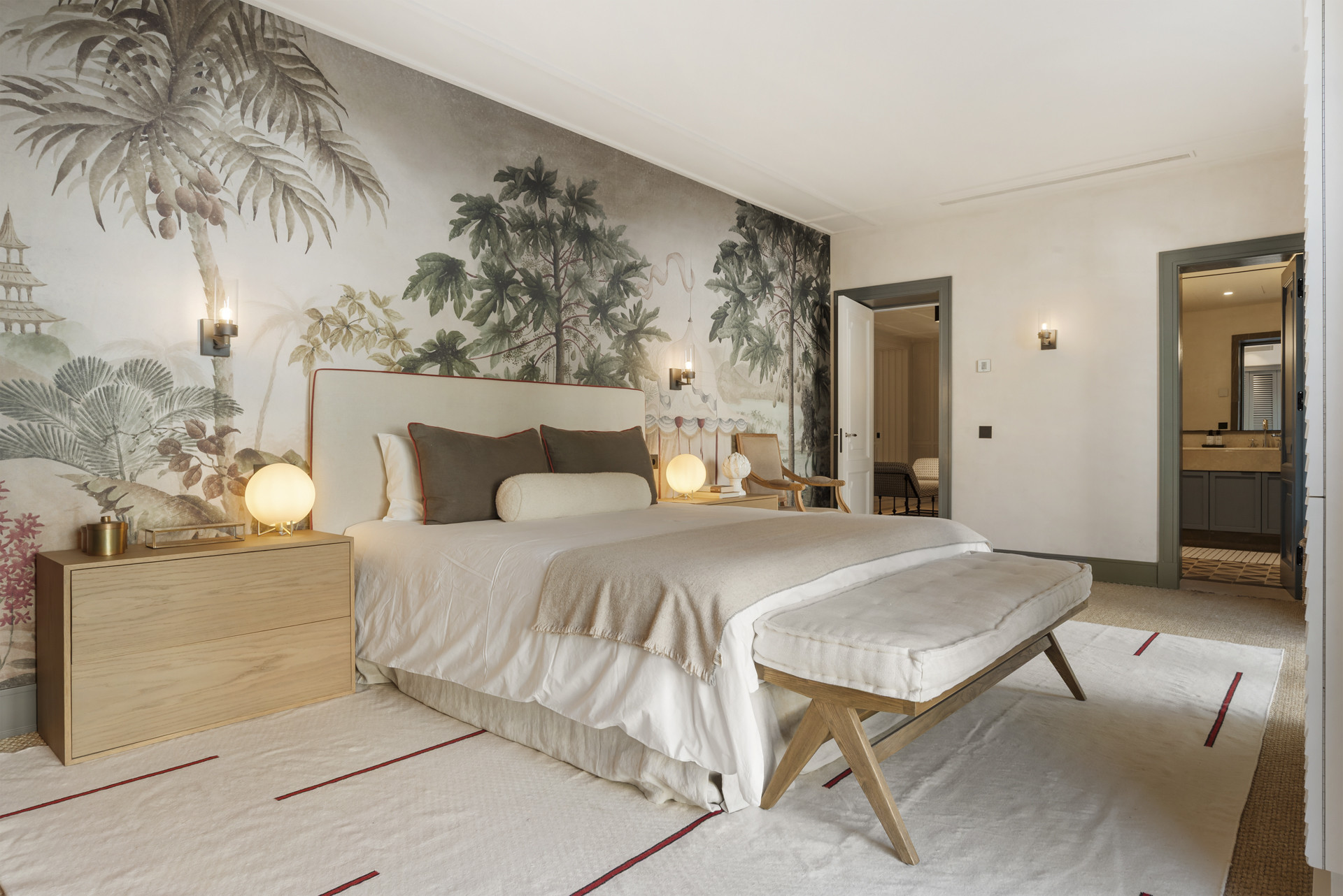 Elegant bedroom featuring a tropical mural, a king-sized bed, and soft lighting.