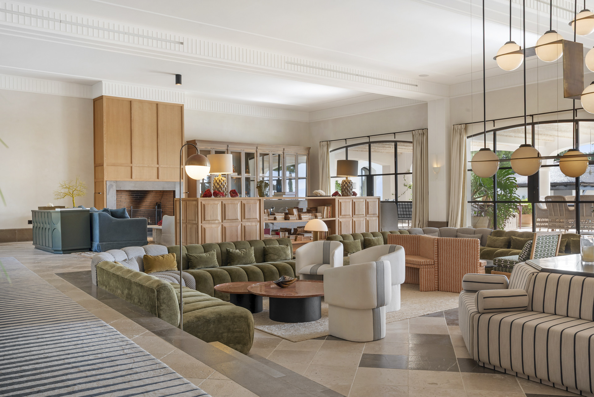 Cozy living space with sectional sofas, fireplace, and stylish lighting in a room with natural light.