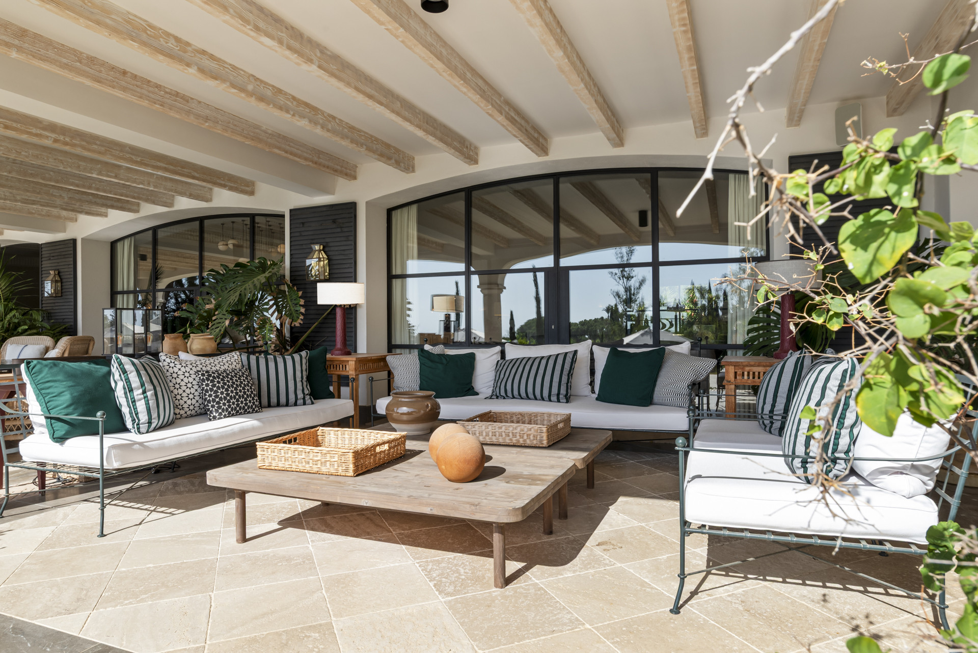Covered lounge area with sofas, decorative pillows, and glass windows.