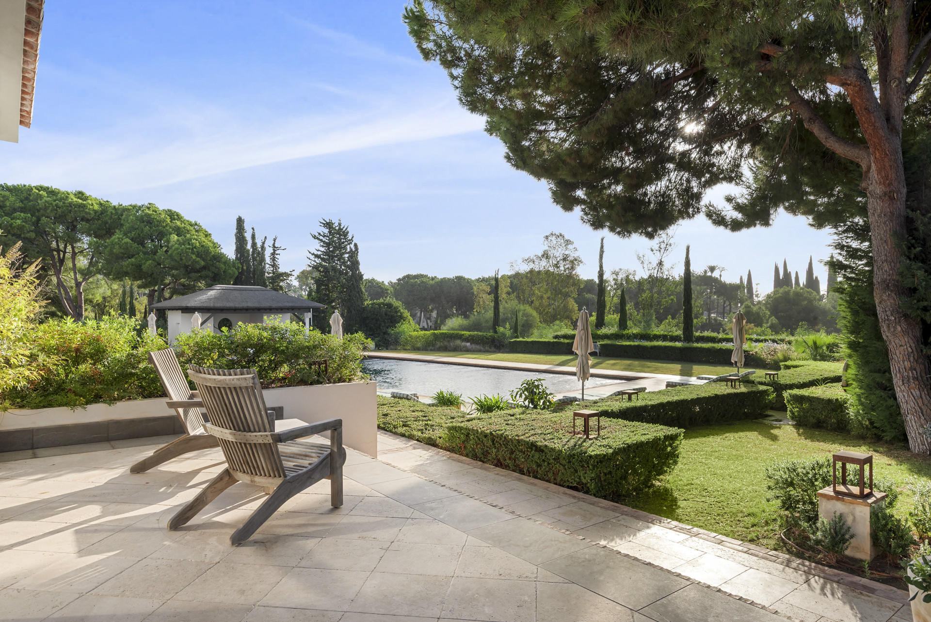 Patio view with lounge chairs and landscaped garden near the pool.