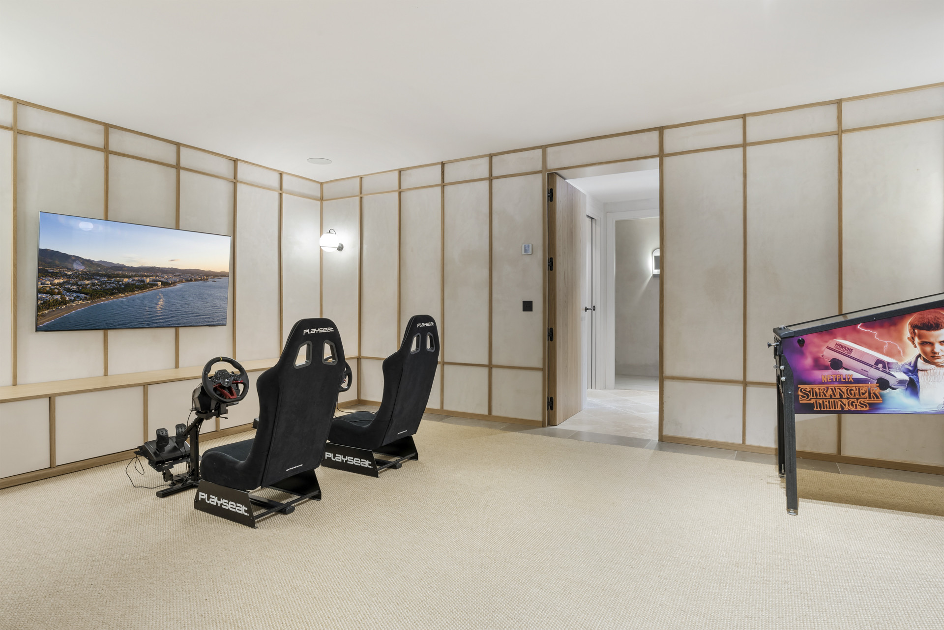 Modern gaming room featuring two racing seats and a large wall-mounted TV.