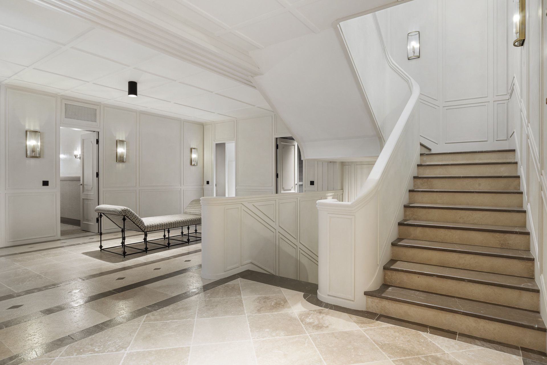 Spacious foyer with a staircase and seating area in a white color scheme.
