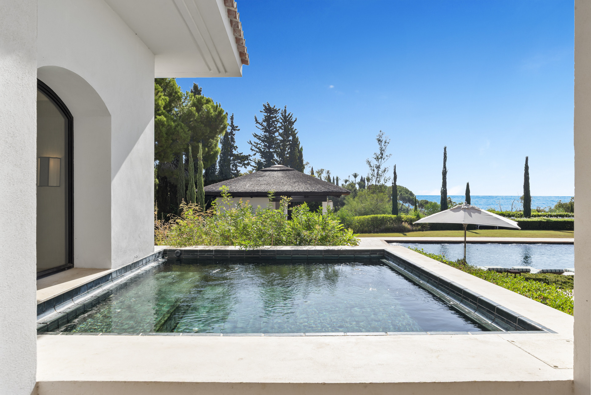 Small plunge pool reflecting trees and an outdoor structure nearby.