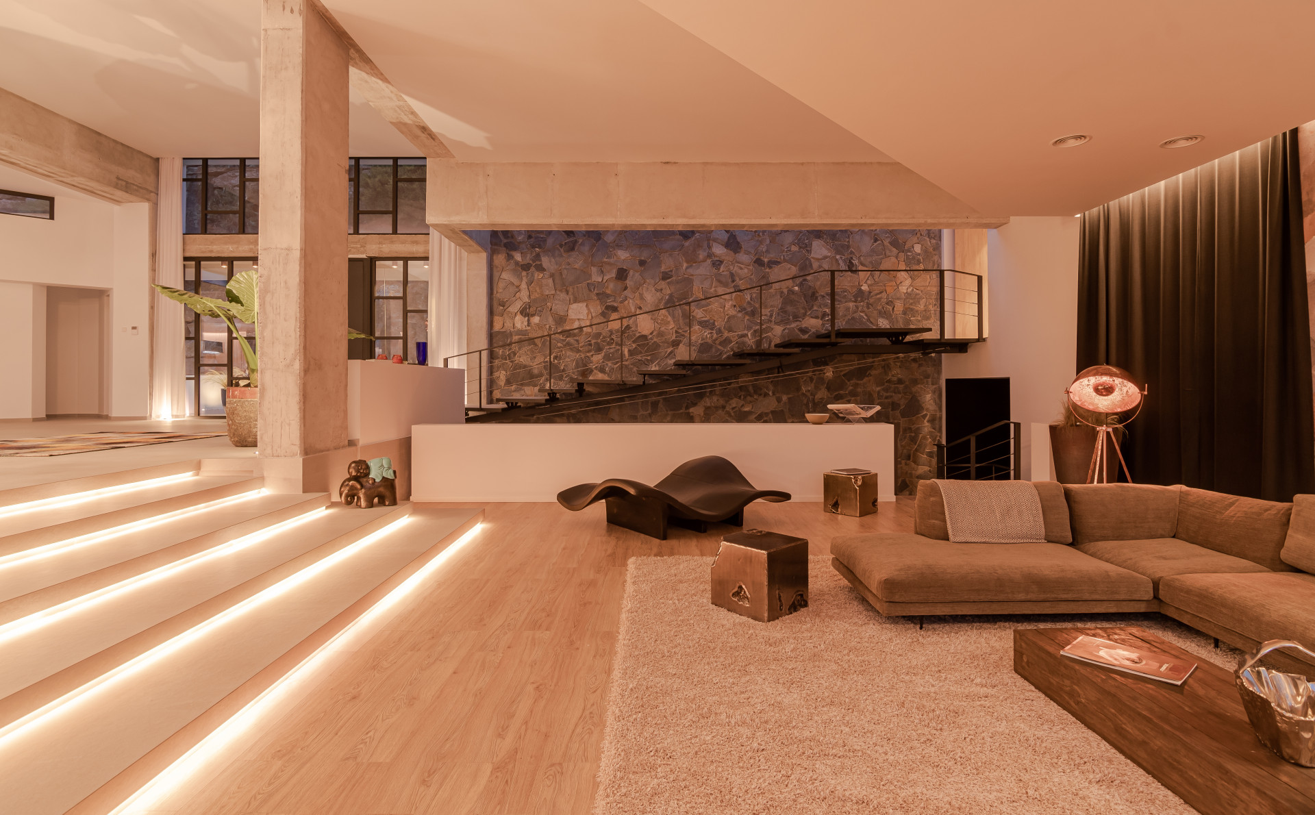 Spacious living room with a textured stone wall, sectional sofa, and modern decor lighting.
