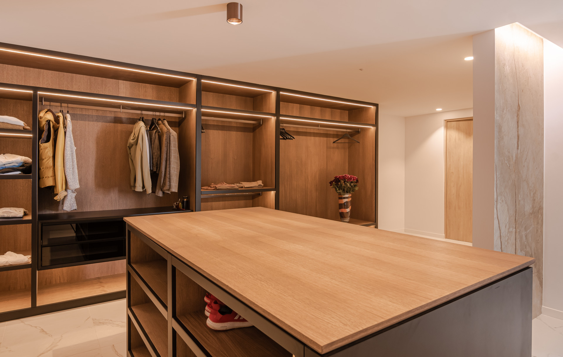 Walk-in closet featuring wooden shelves, hanging space, and a central island for storage.