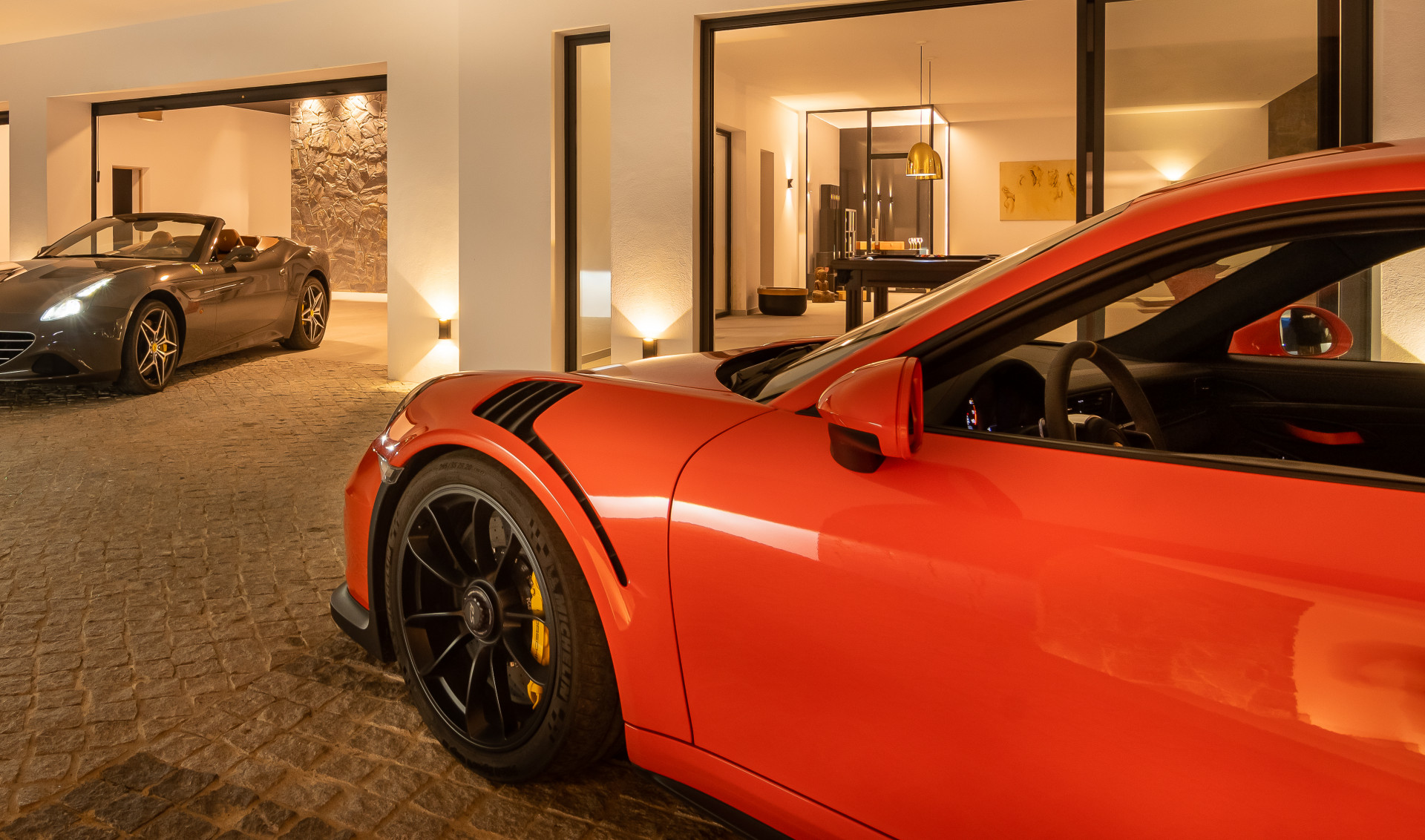 Two luxury cars parked in a well-lit garage area