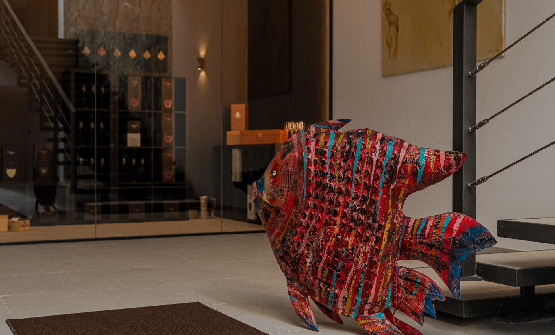 Colorful fish sculpture at the entrance, with stairway and glass display shelves in the background.