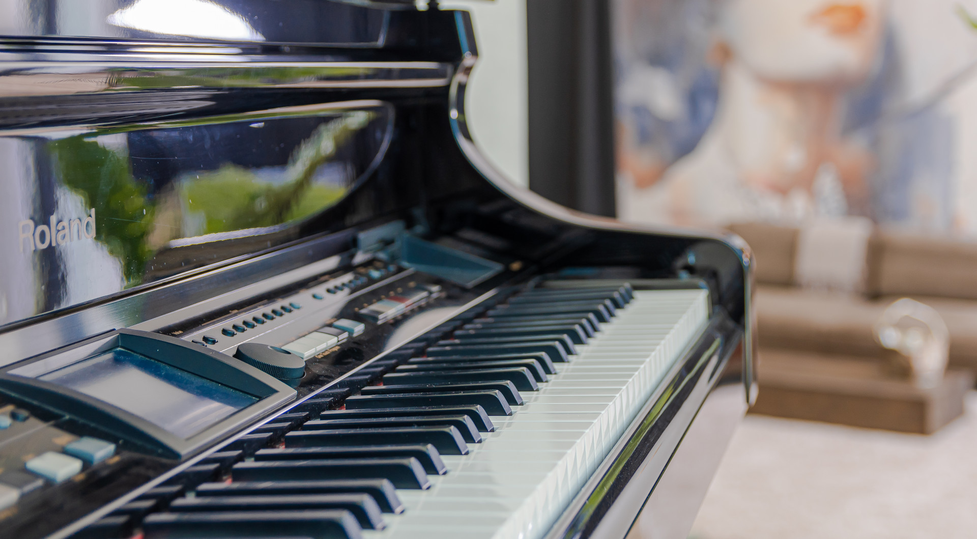 Close-up of a black piano's keys and controls with blurred background