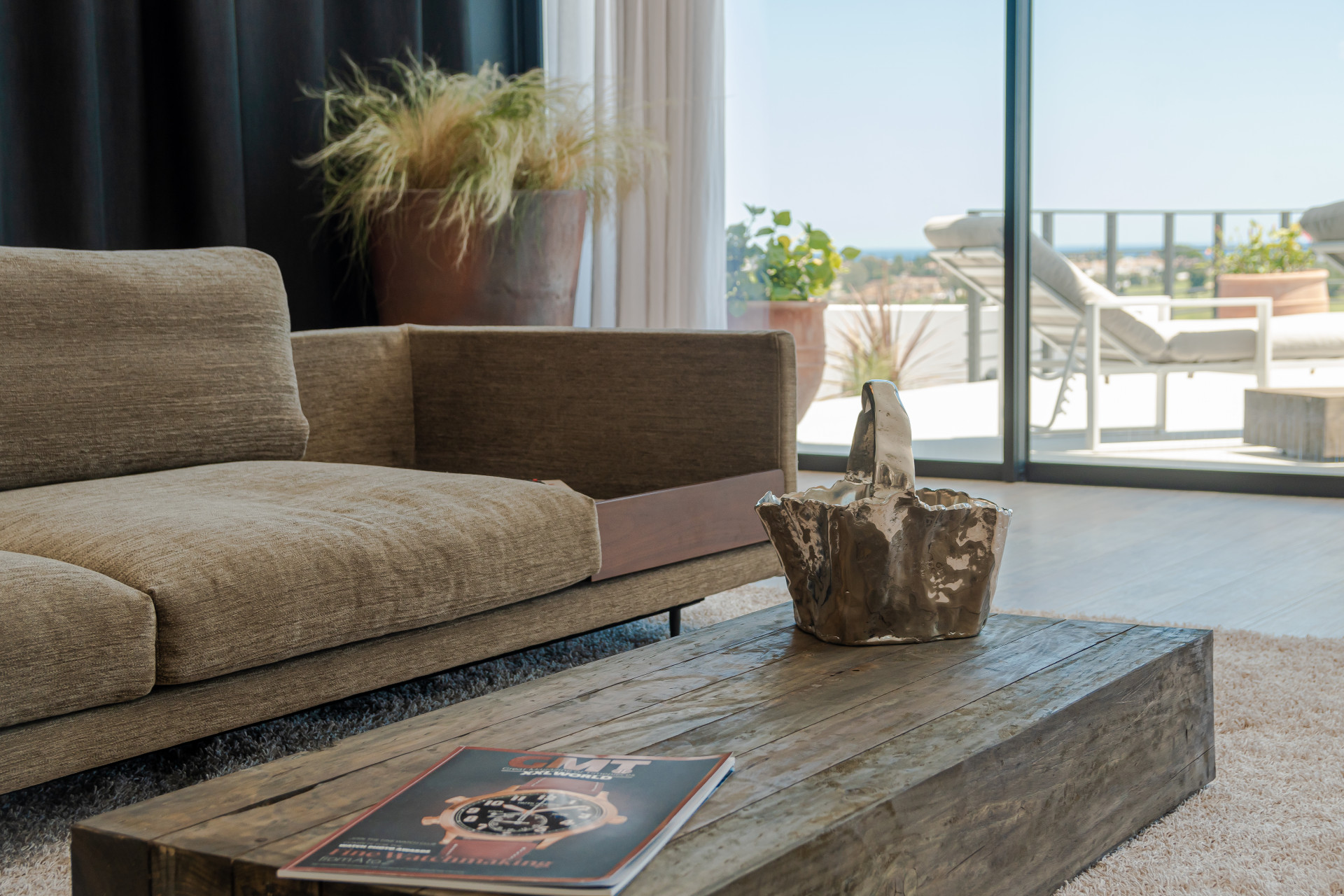 Living room view with a couch, coffee table, and glass doors to terrace