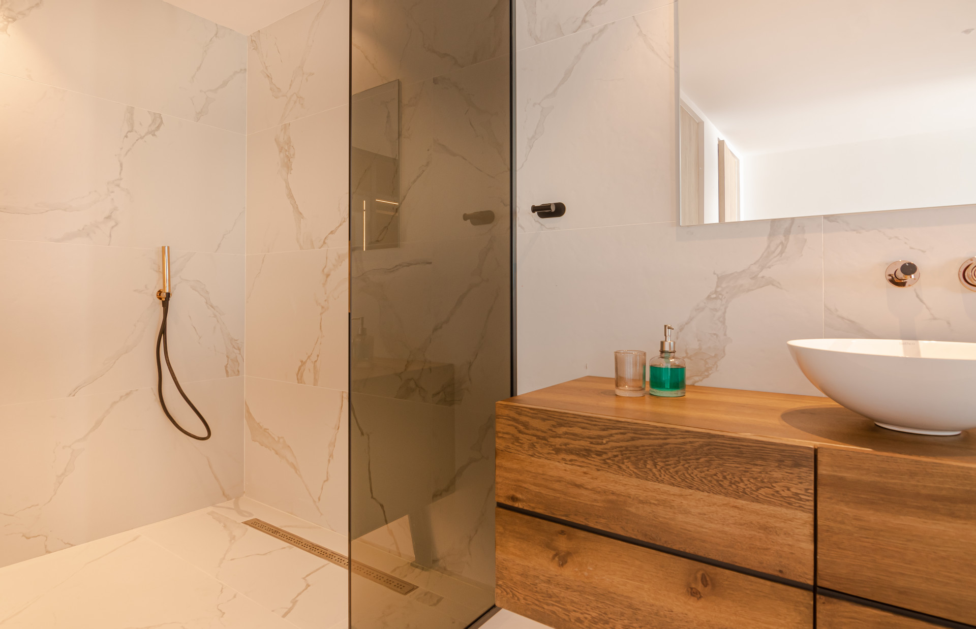Shower area featuring a marble wall, glass door, and stylish fixtures