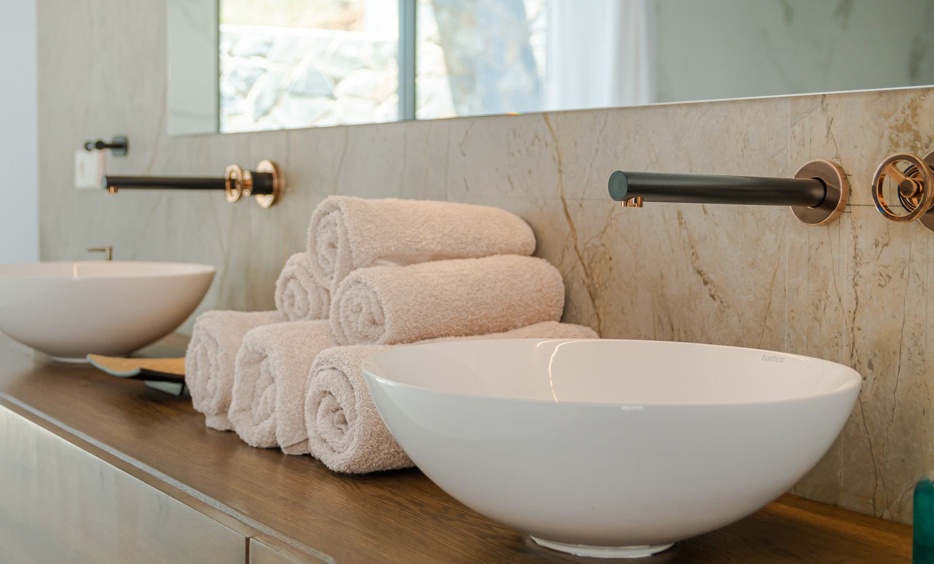Stylish bathroom countertop with two bowls, neatly arranged towels, and a wall-mounted mirror.