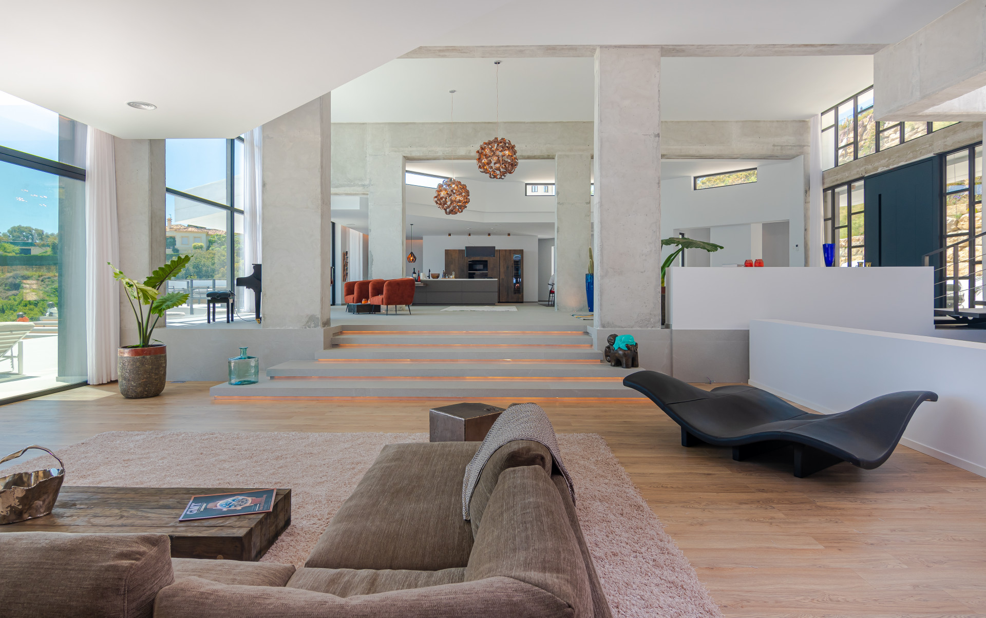 Open concept space featuring modern furniture, large windows, and stylish pendant lighting.