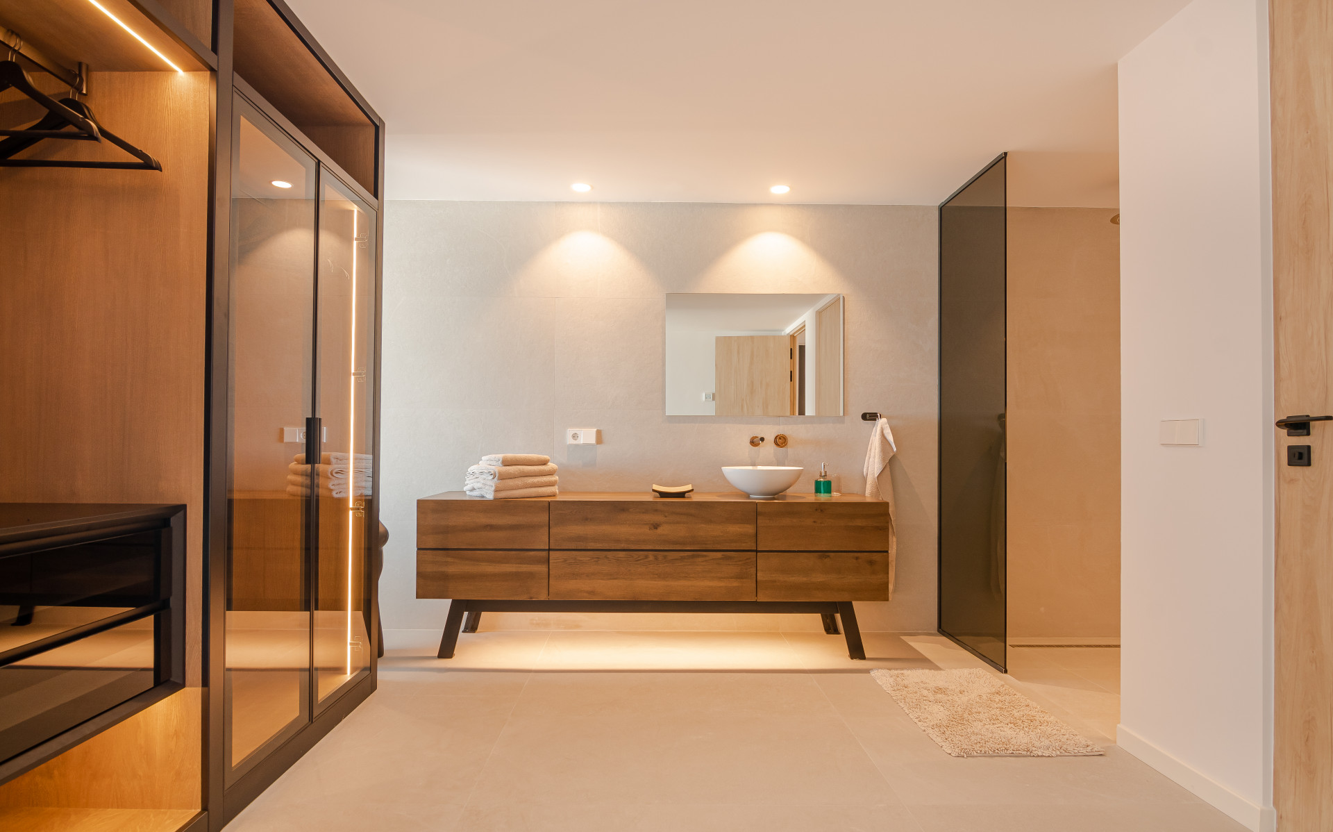 Modern bathroom with wooden vanity, towels, and glass shower