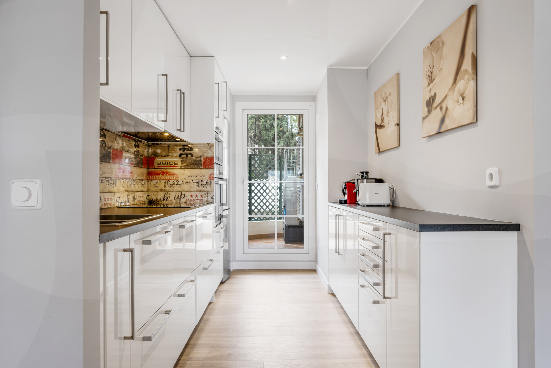Gleaming kitchen with white cabinets, stainless steel appliances, and access to outdoor patio.