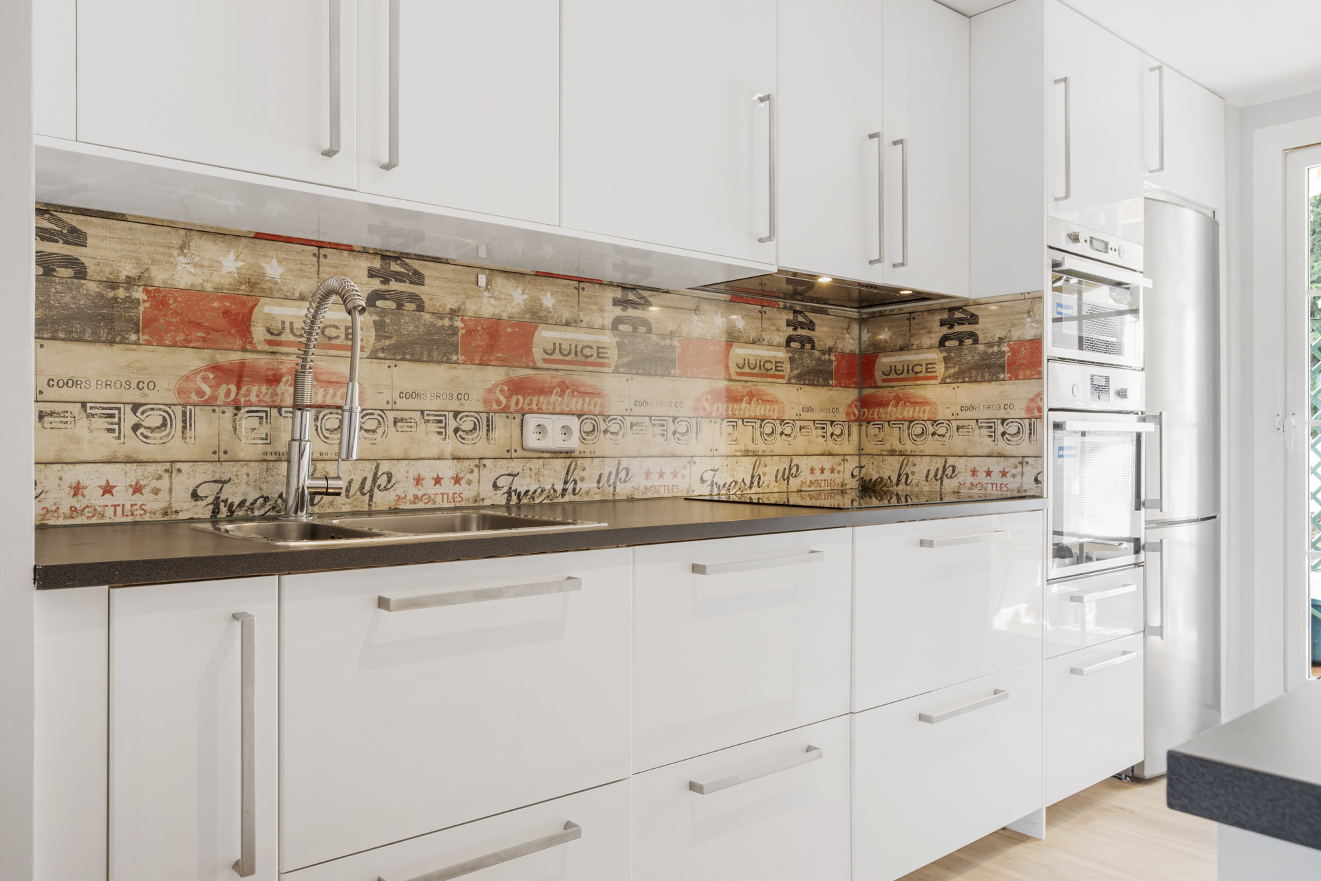 Close-up of kitchen counters with artistic backsplash and modern fixtures.