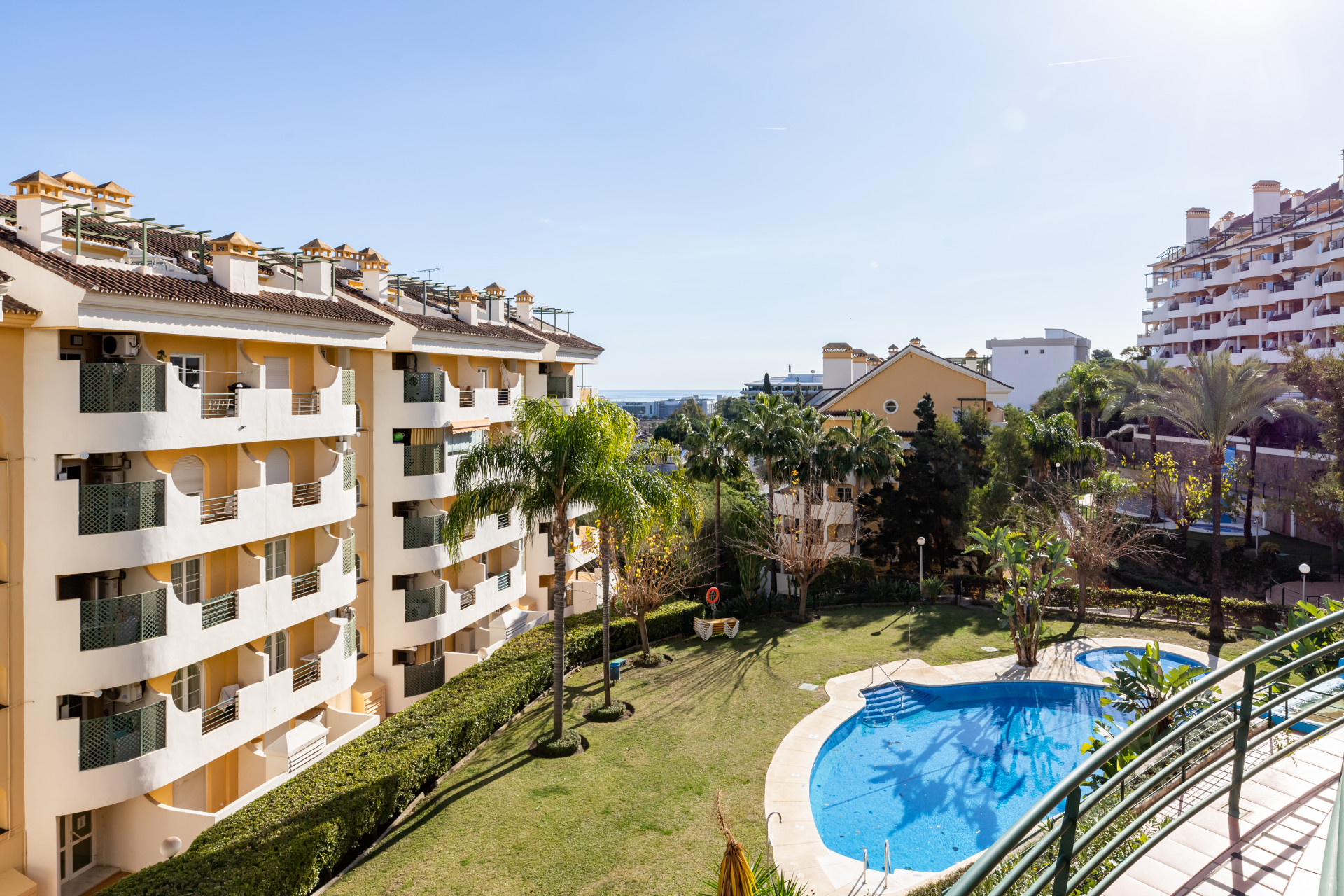 View of the pool area and surrounding buildings in Marbella under clear blue skies.