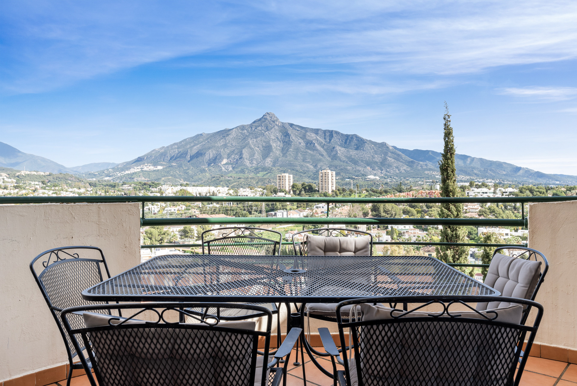 Terrace with a dining table overlooking mountains and cityscape in Marbella.