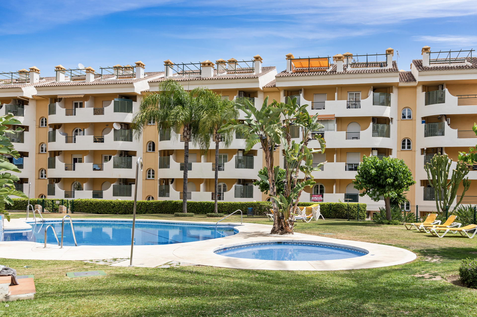 View of the apartment buildings and poolside greenery in the Marbella complex.