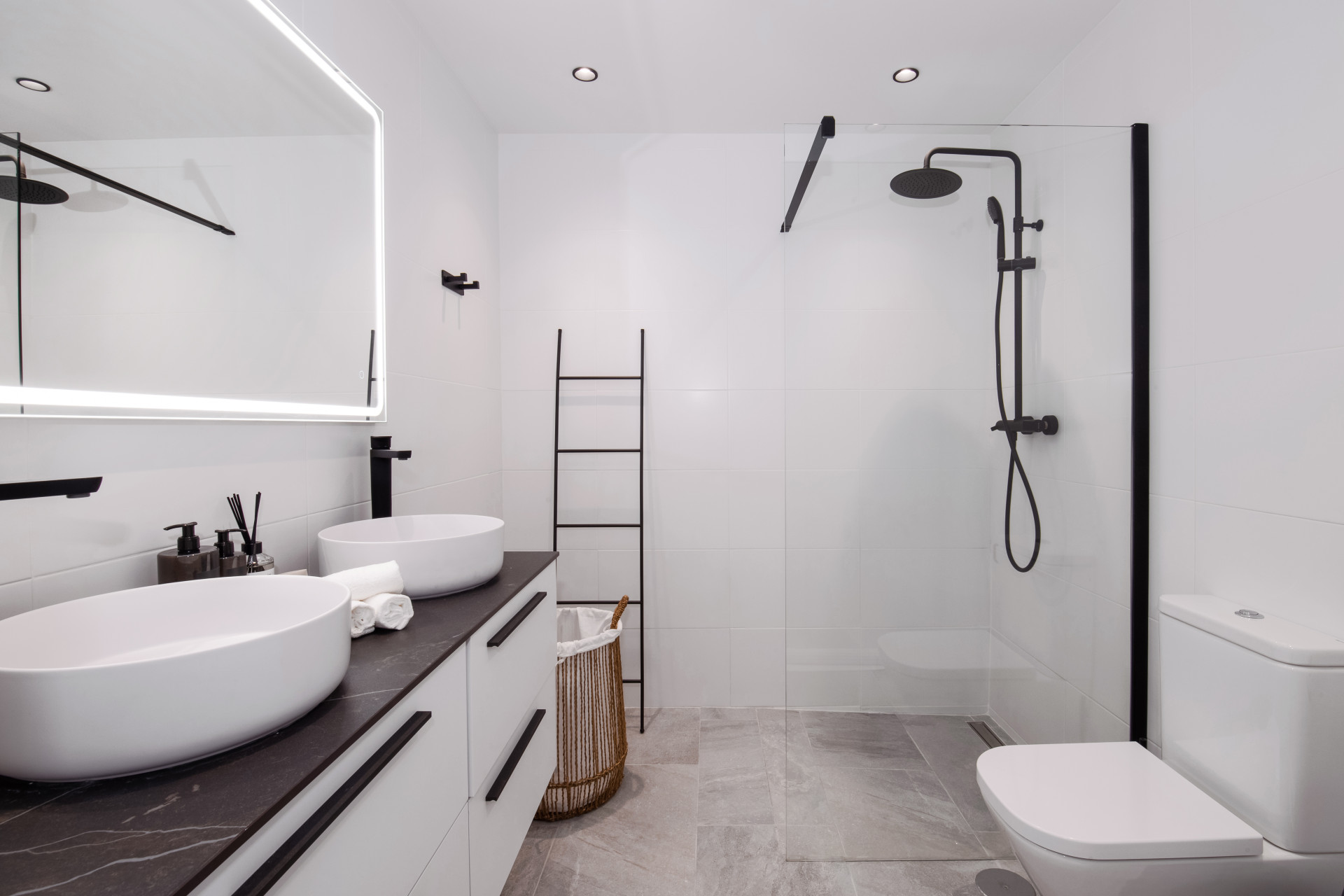 Sleek bathroom with dual sinks, shower, and modern fixtures in a neutral color scheme.