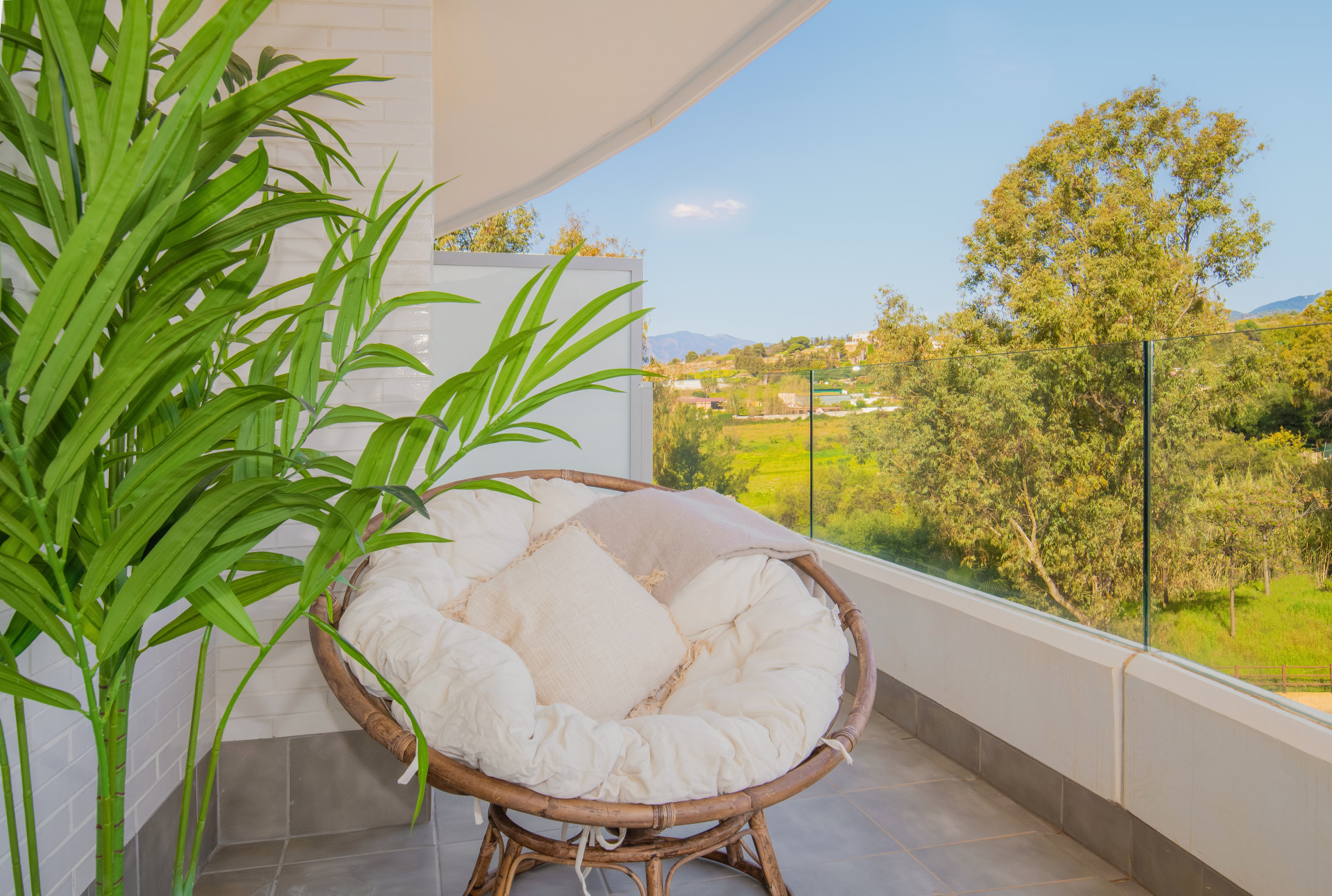 Close-up of a cozy chair on the balcony, with greenery and a view of the hills outside.