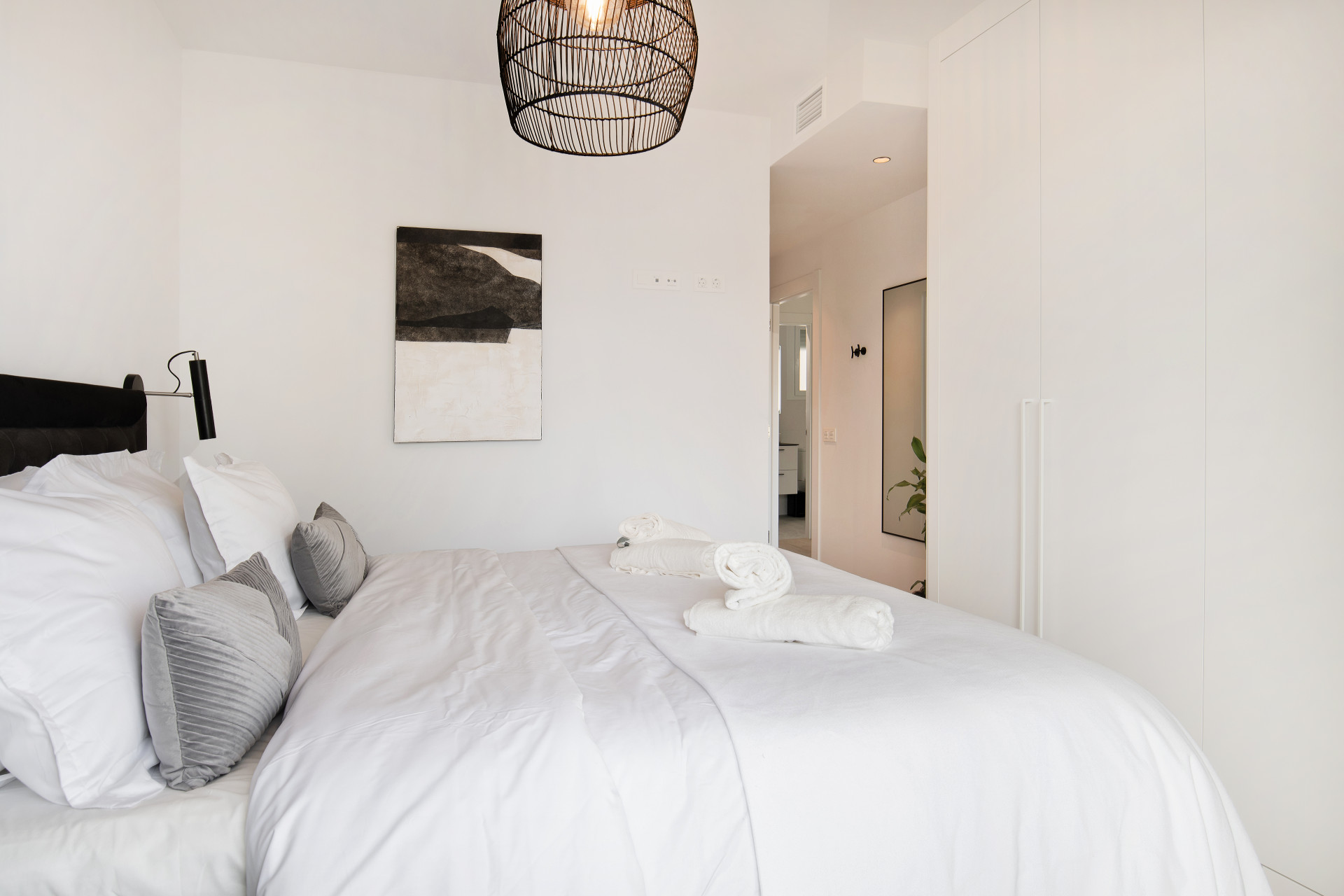 Another bedroom featuring a bed with decorative pillows, a modern light fixture, and closet space.