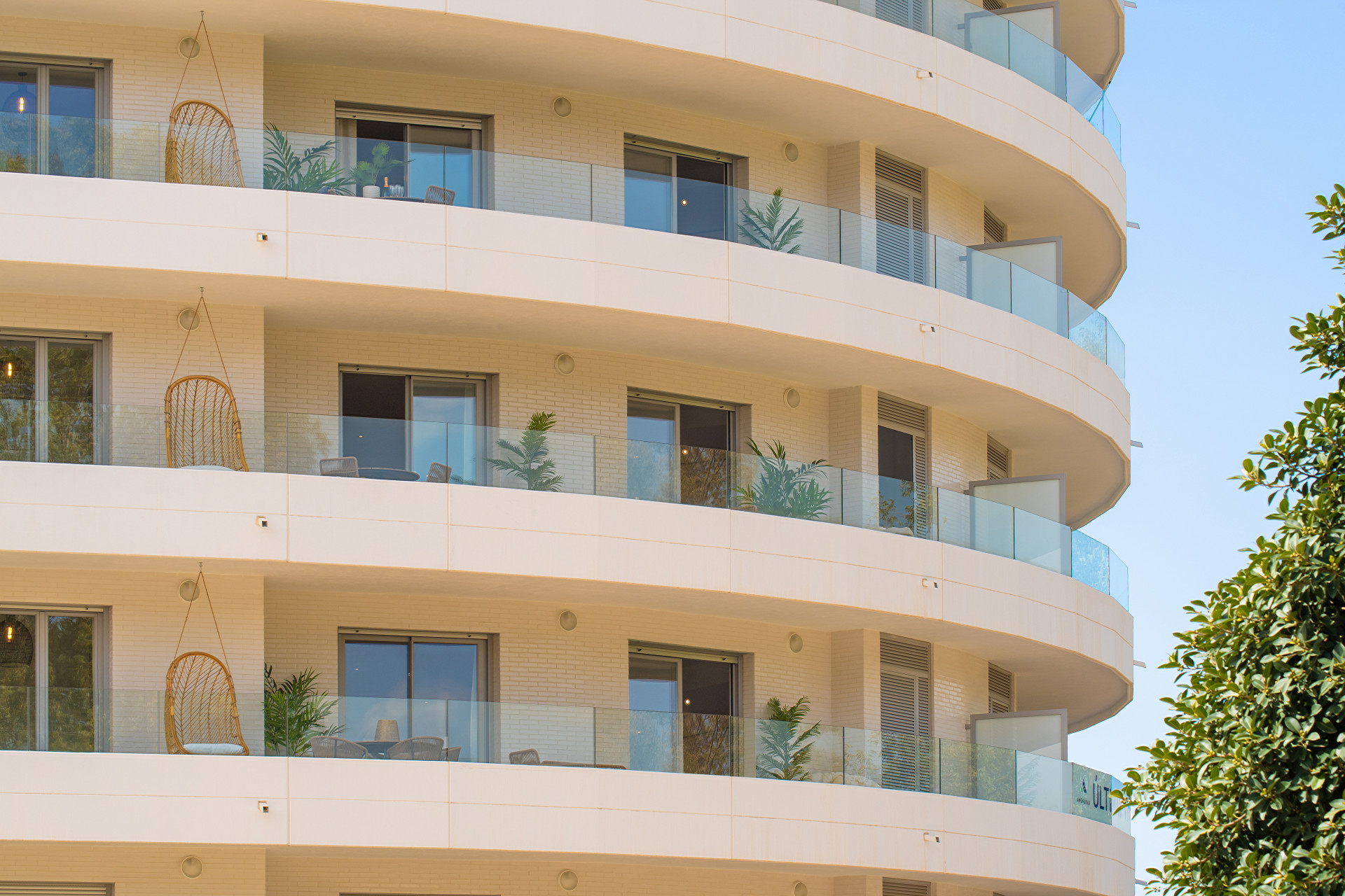 Close-up of modern balconies featuring hanging chairs and greenery on a circular building.
