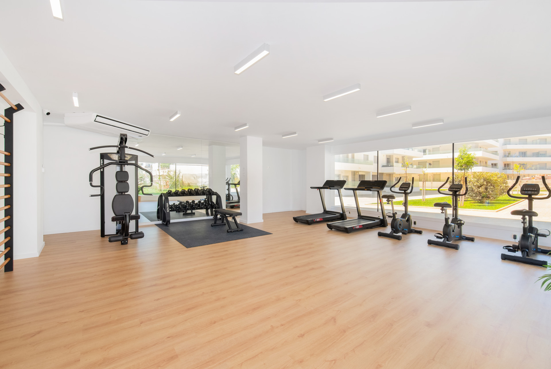 Bright gym area with fitness equipment and large windows overlooking the outdoor space.