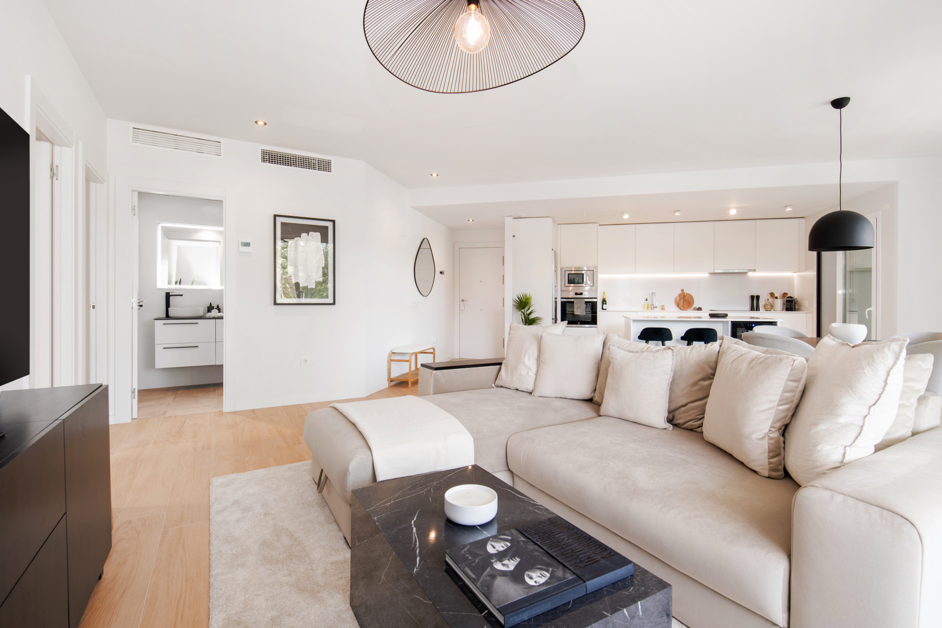 Living room with a sectional sofa, coffee table, and entrance to the kitchen area visible.
