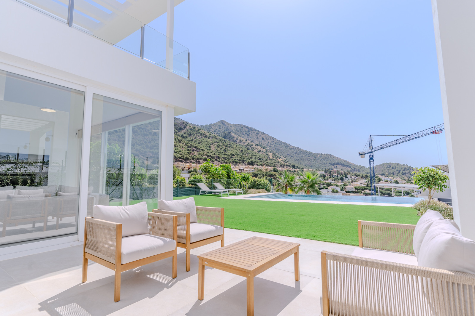 Terrace with seating and pool view, surrounded by greenery and mountains.