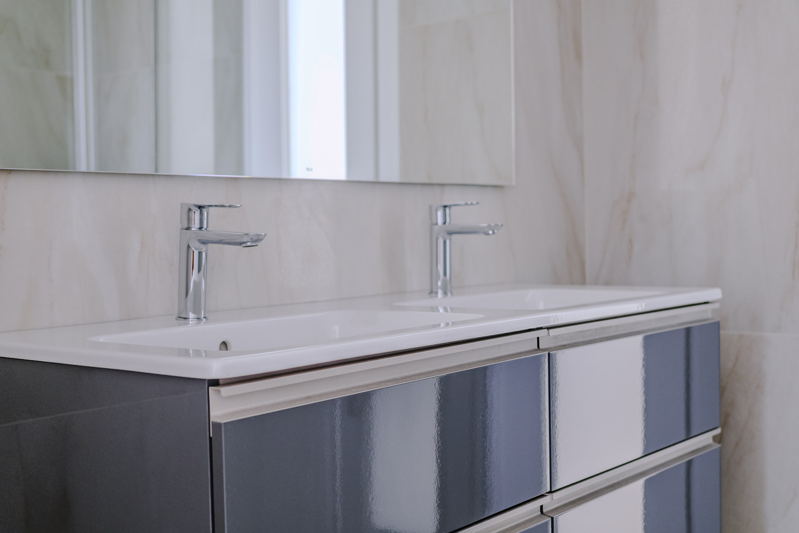 Modern bathroom with dual sinks and sleek cabinetry.