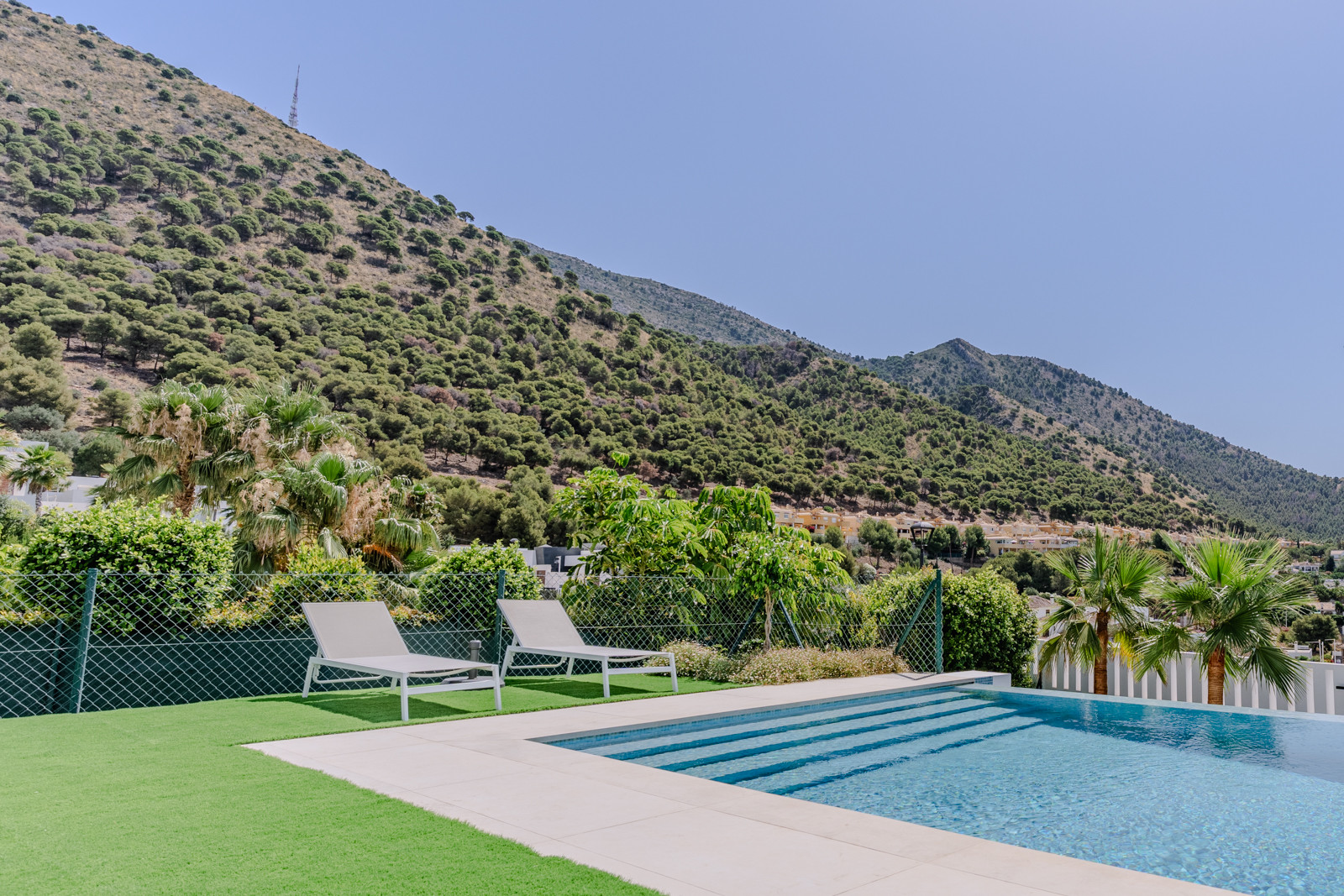 View of the pool area with loungers and mountains in the background.