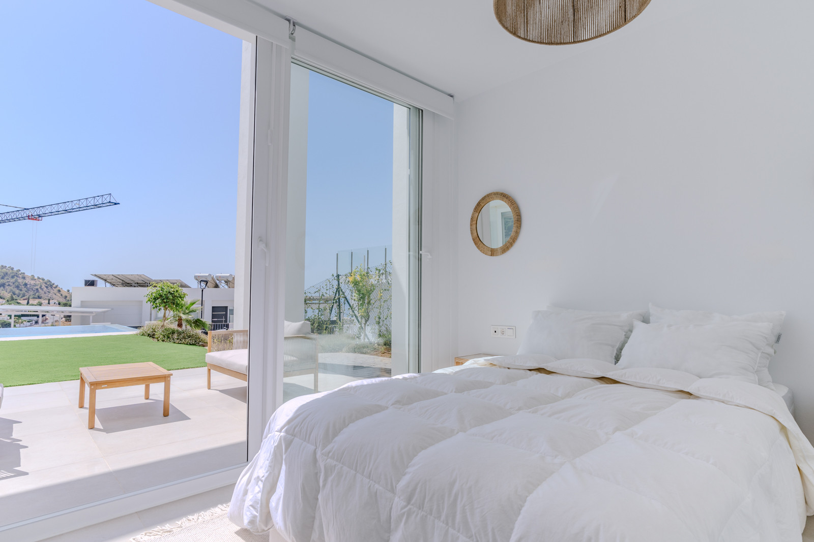 Cozy bedroom with a large window overlooking the garden, featuring a minimalistic design.