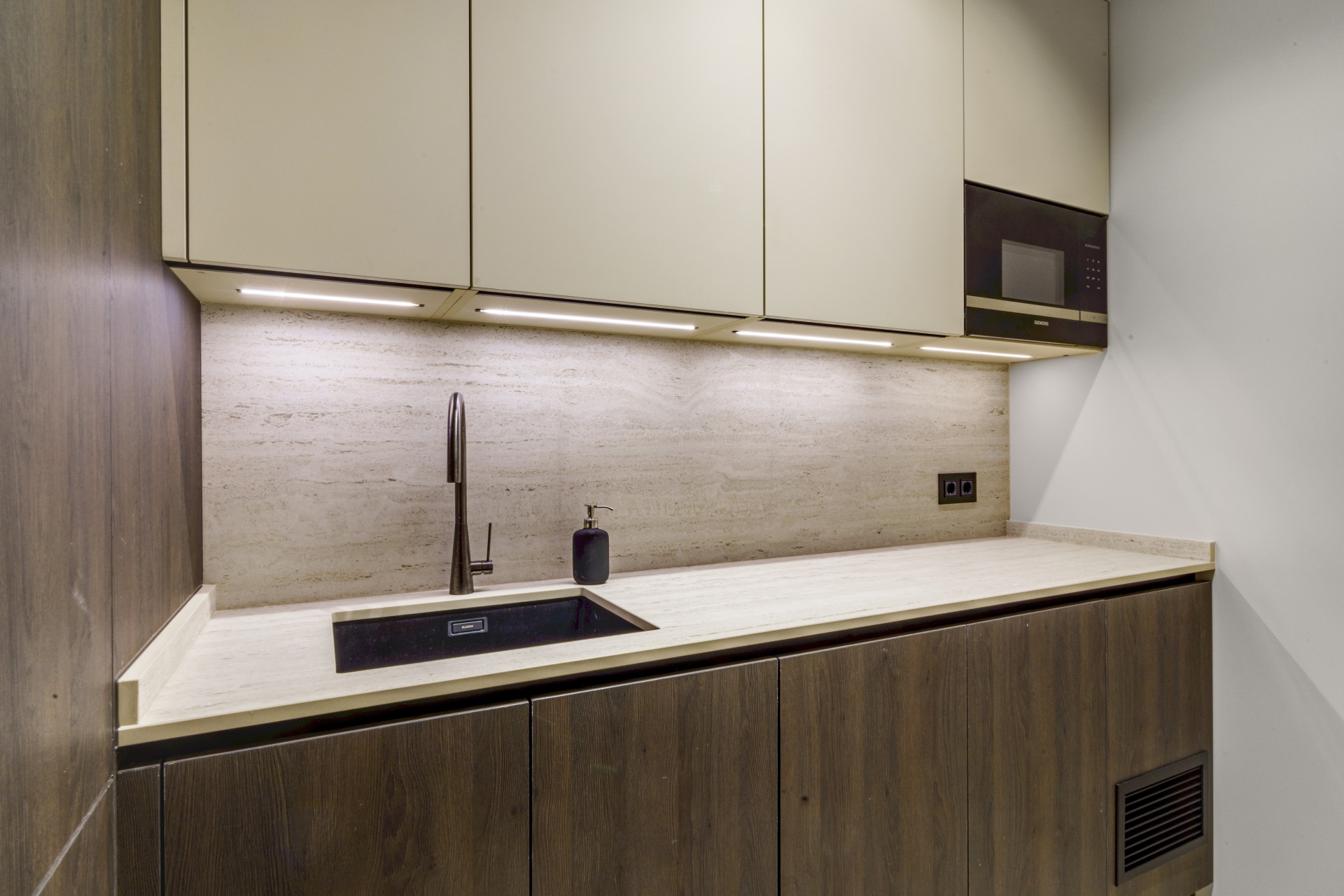 Modern kitchenette with overhead cabinets, counter space, and a sleek sink.