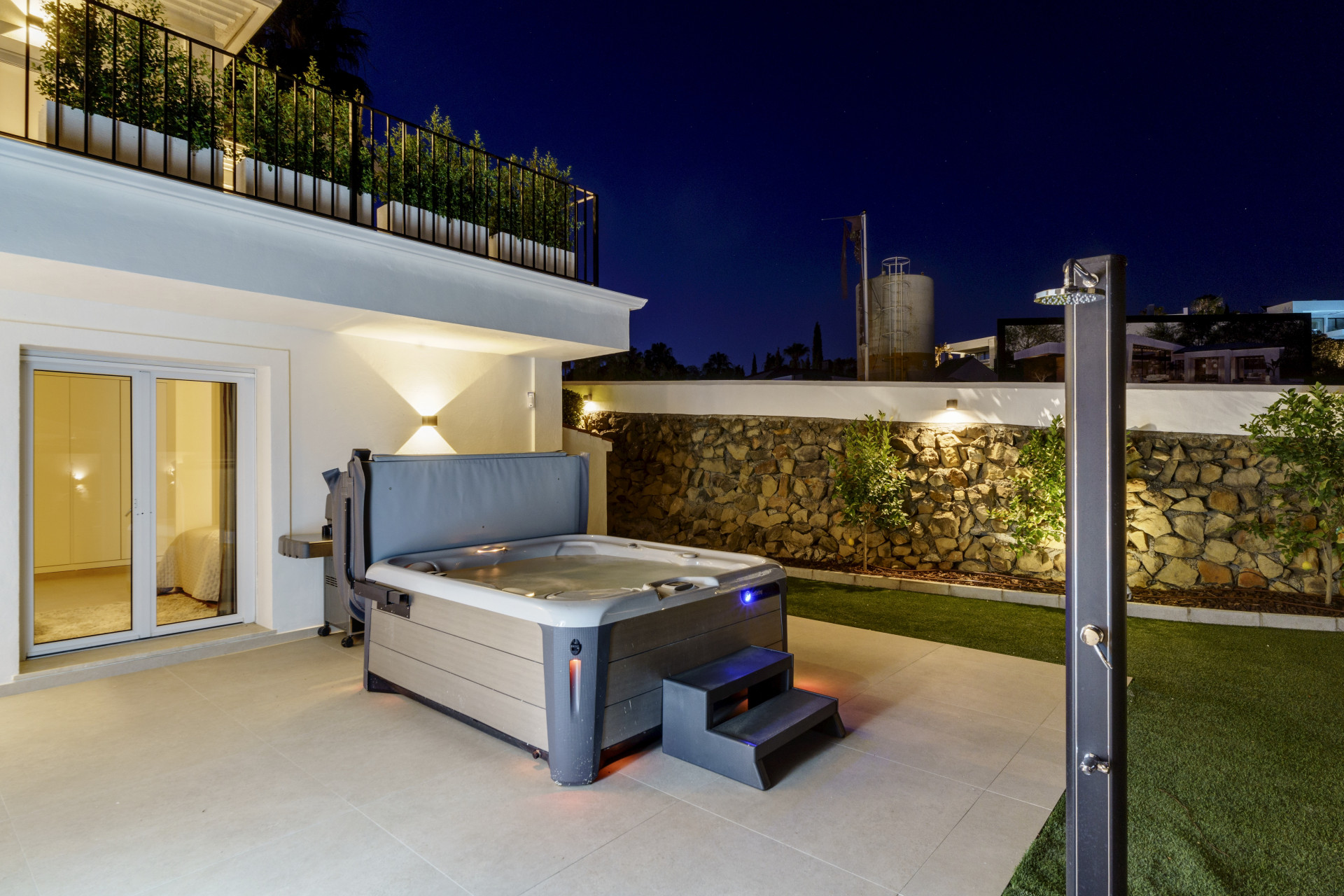 Outdoor area with a hot tub, patio space, and landscaped wall lighting.